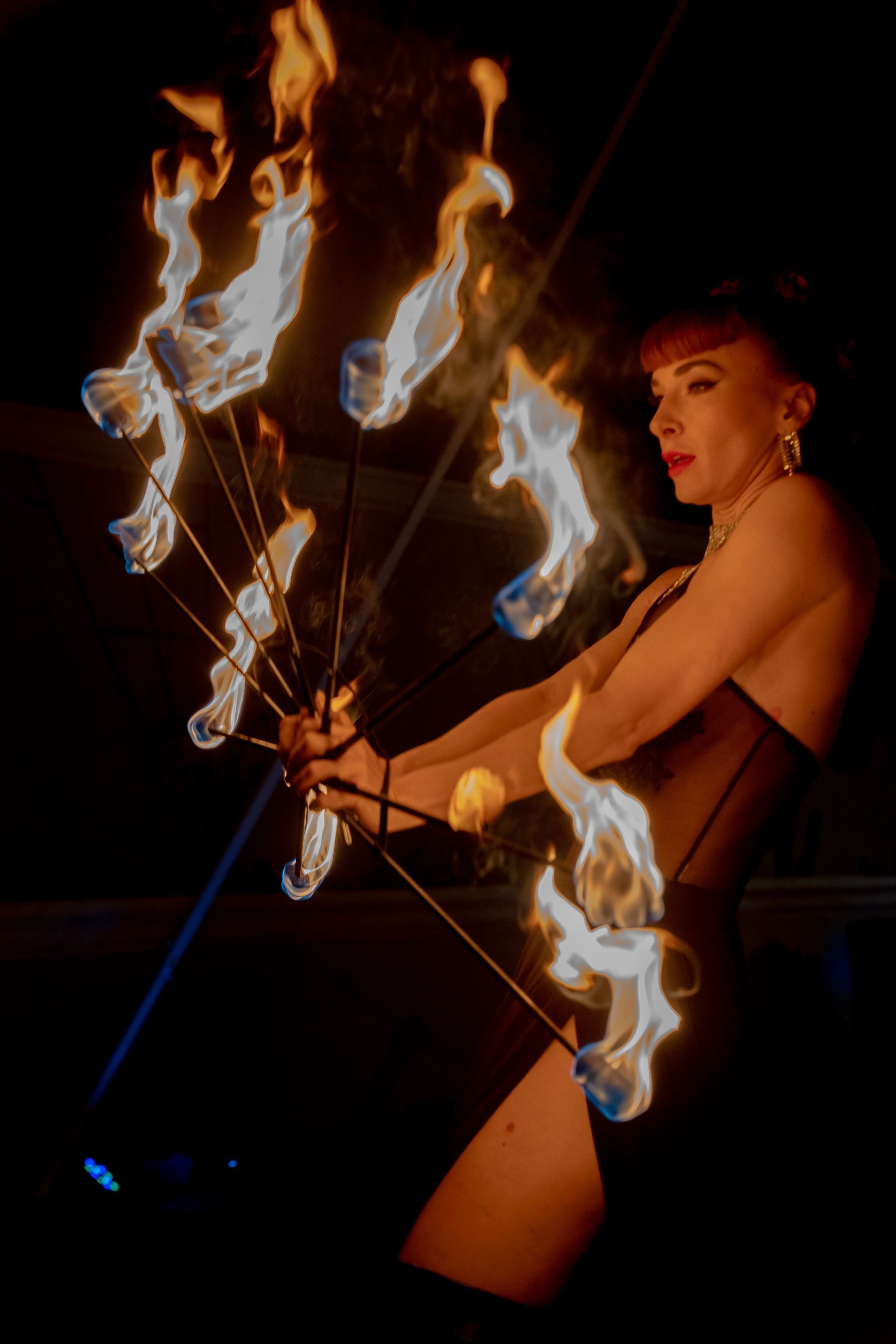 A woman in a black dress is holding a bunch of flames.