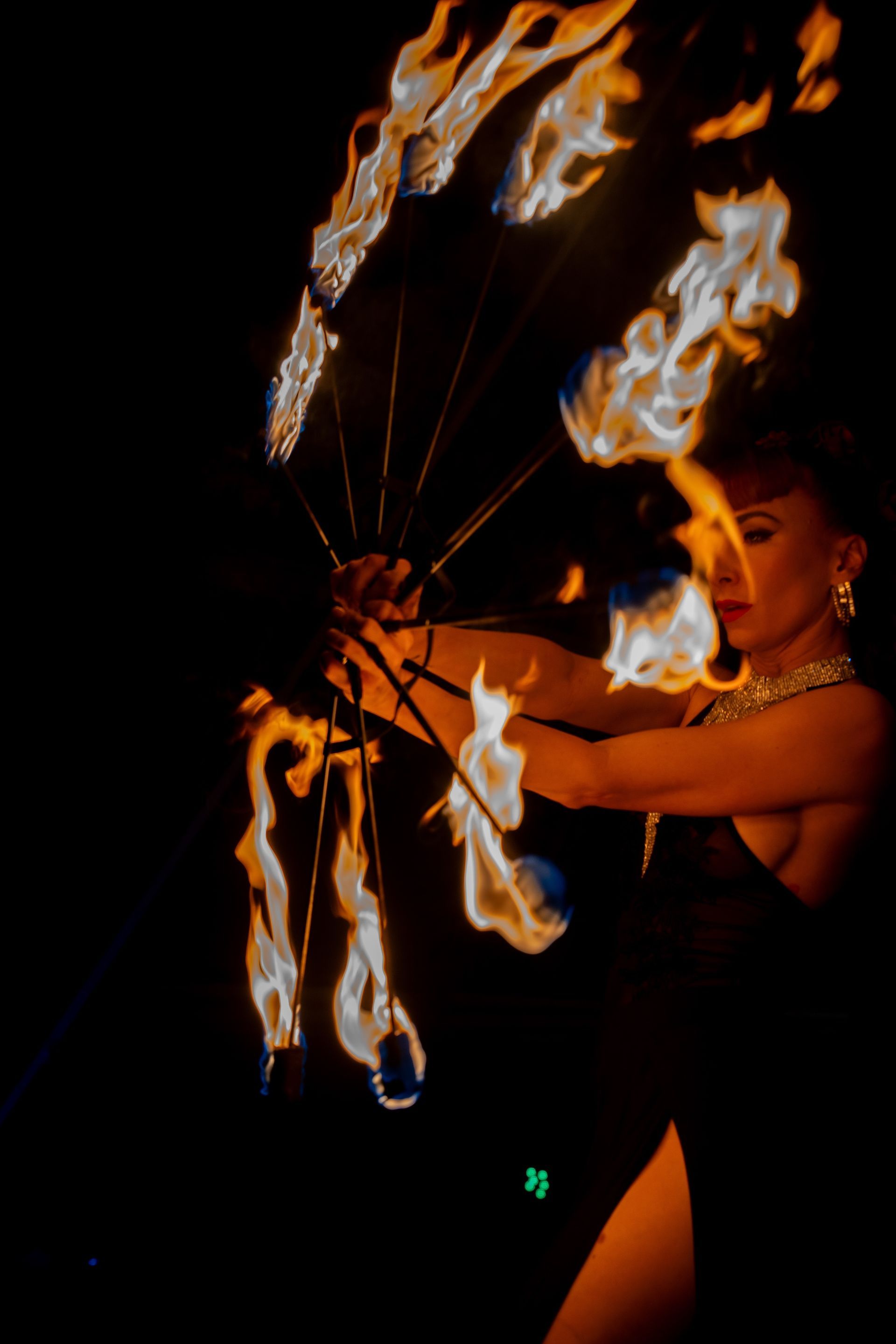 A woman in a black dress is holding a fan of fire.