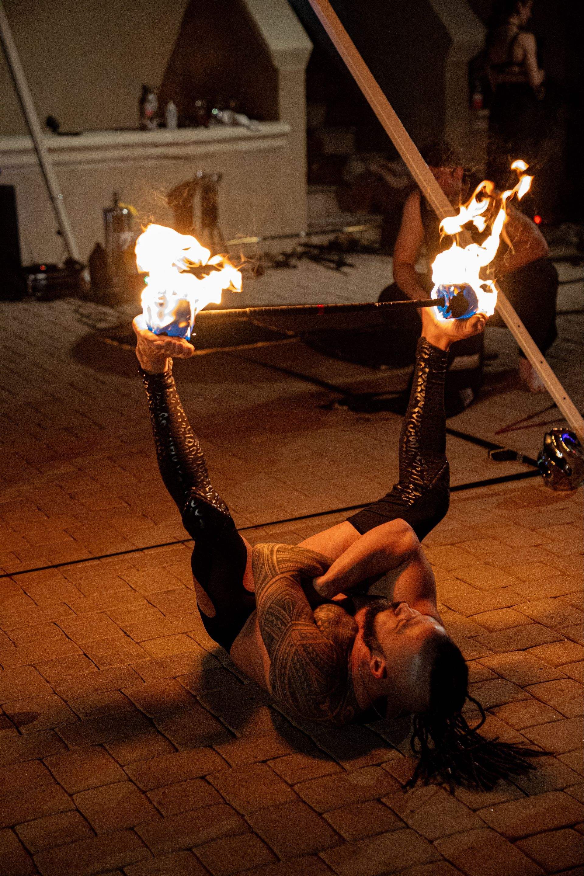 A man is laying on the ground holding a fire stick