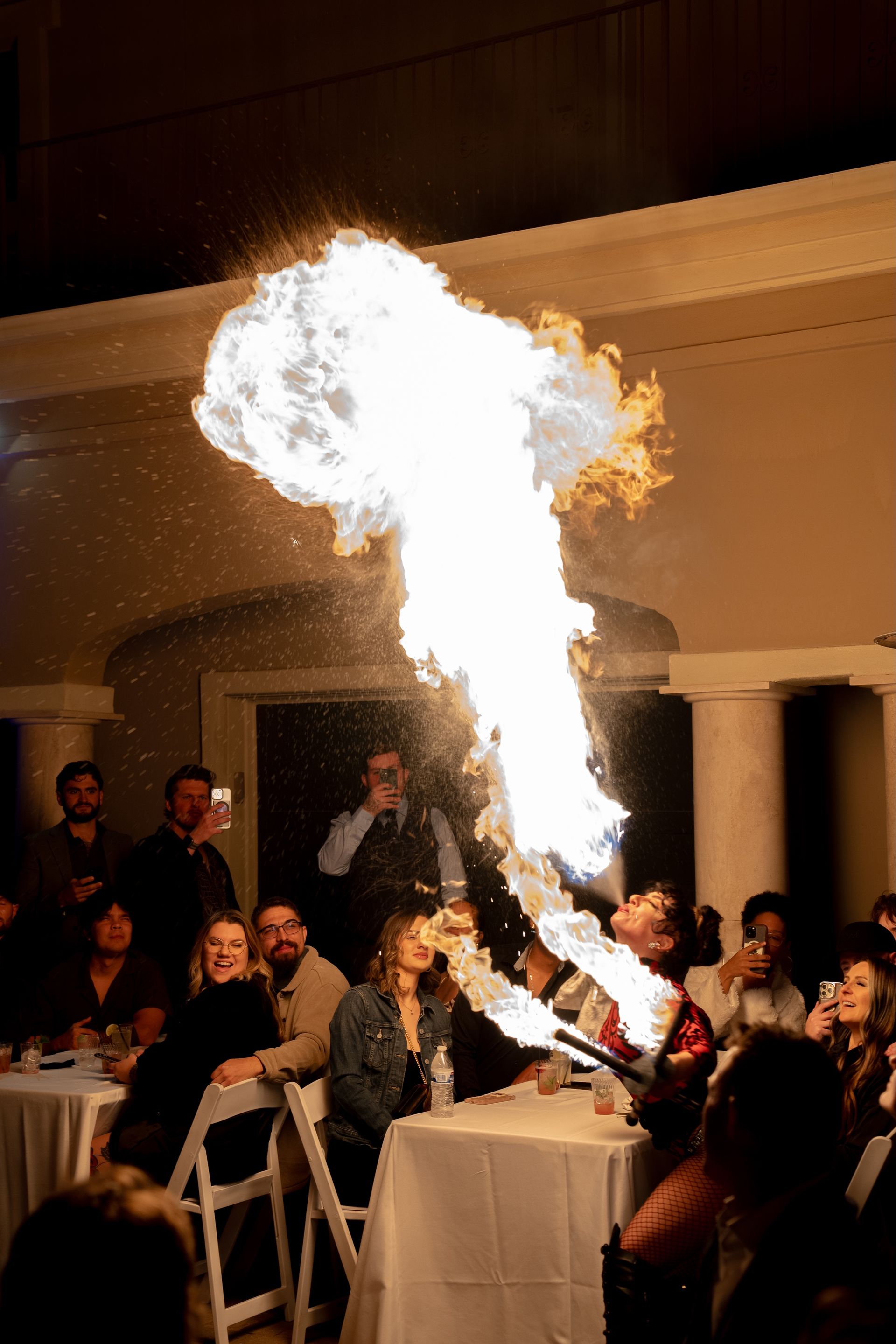 A group of people are sitting at tables watching a fire show.
