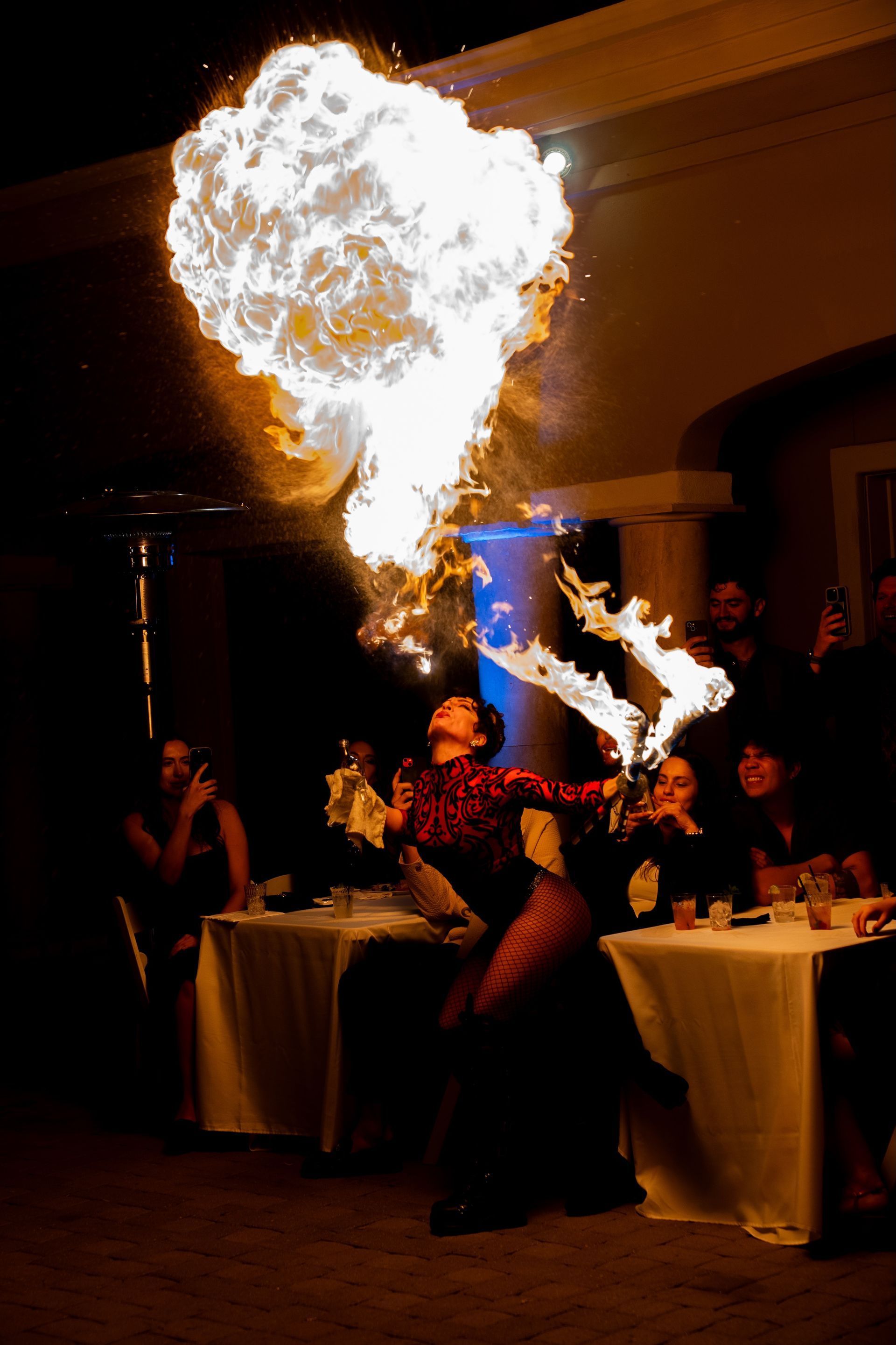 A woman is blowing fire into the air at a party.