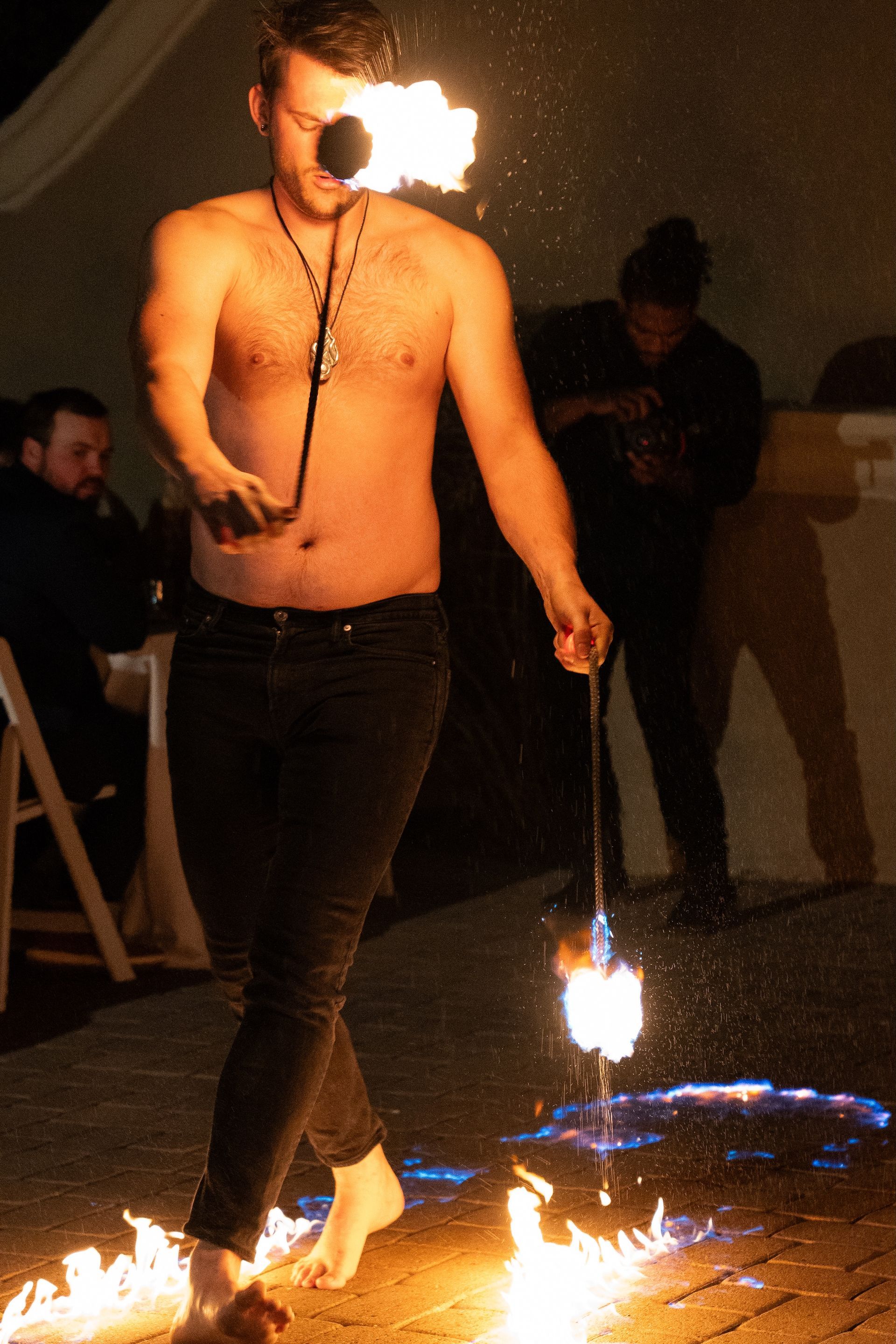 A shirtless man is walking through a circle of fire.
