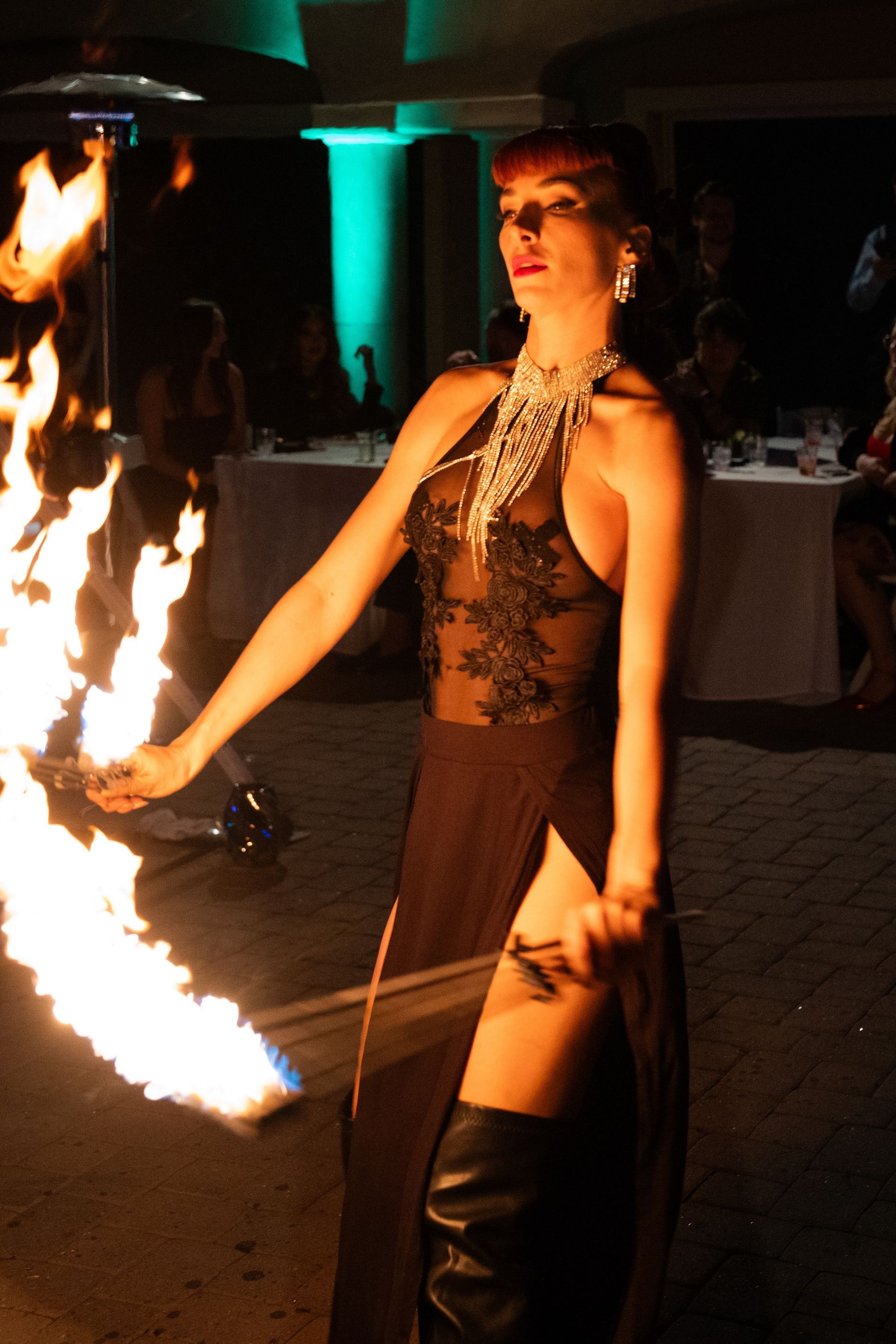 A woman in a black dress is holding a torch with flames coming out of it