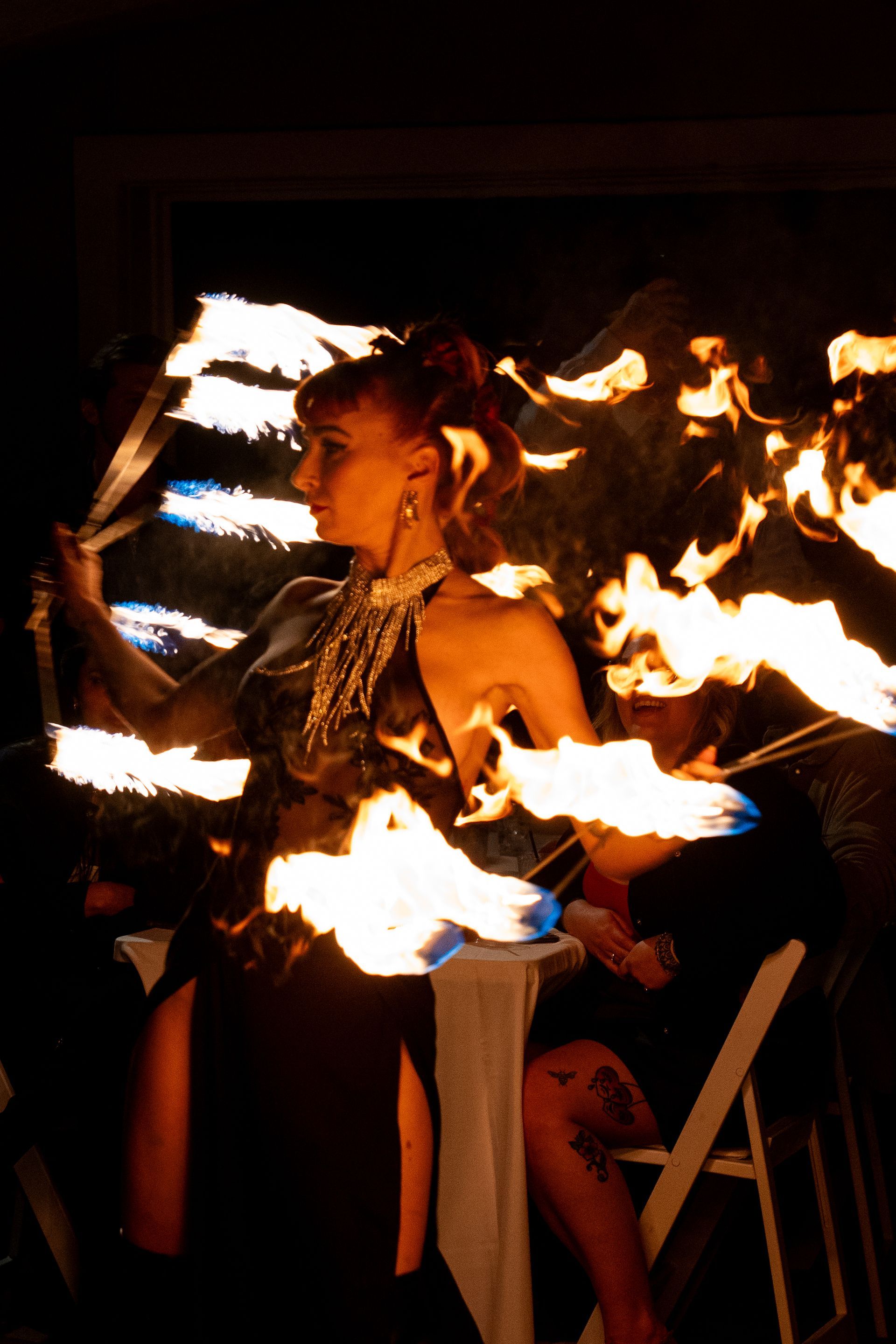 A woman in a black dress is holding a fan with flames coming out of it