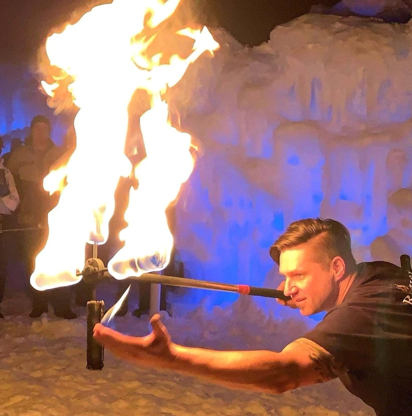 A man is holding a stick with flames coming out of it