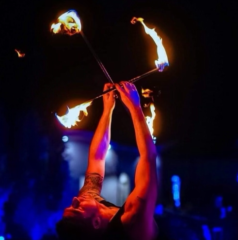 A man is juggling fire sticks in the dark
