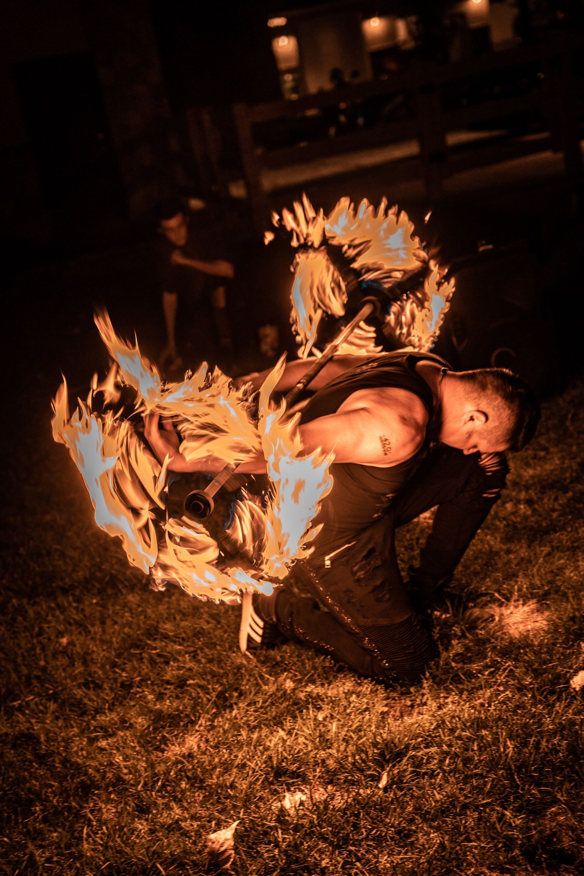 A man is kneeling down in the grass with a torch in his hand.