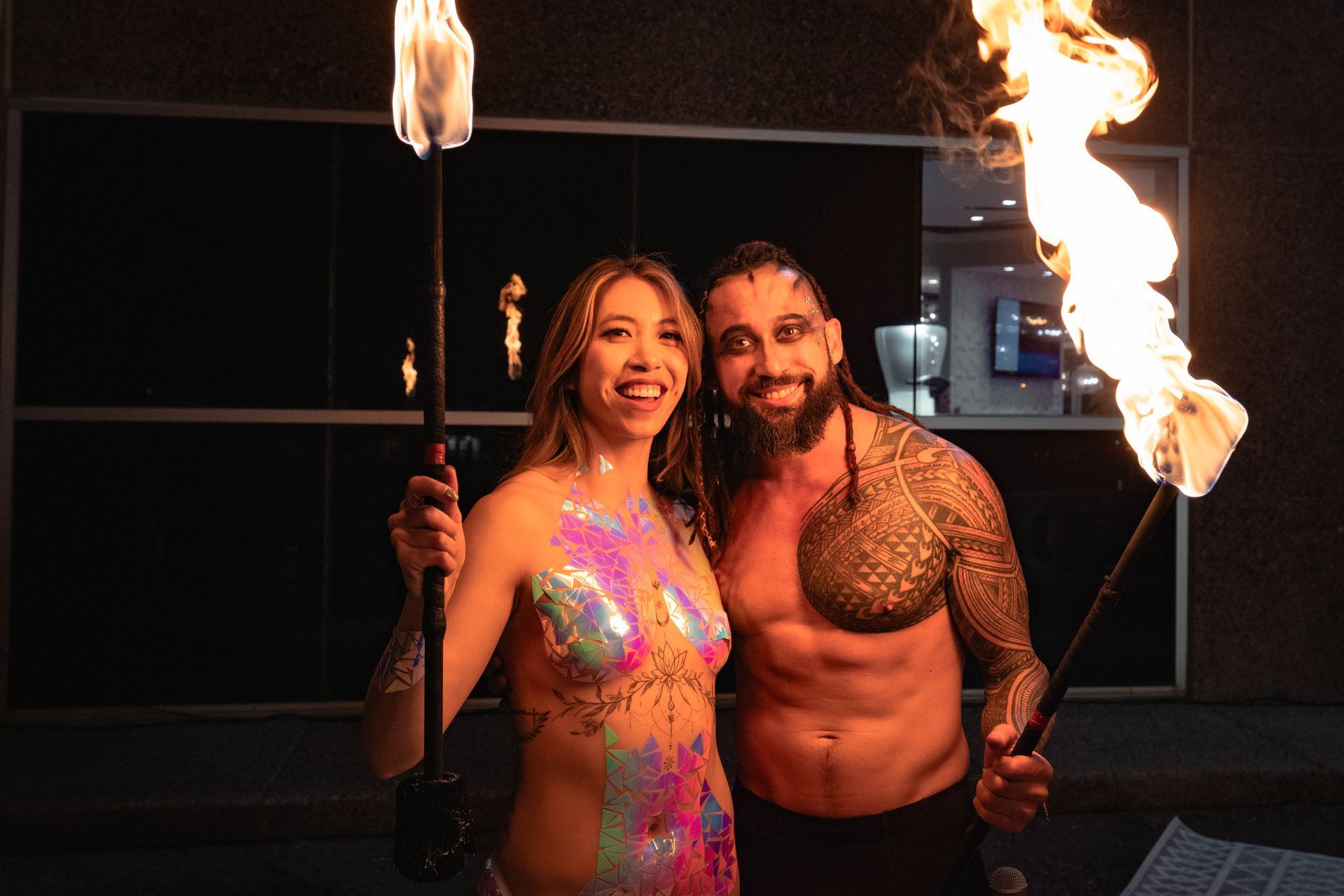 A man and a woman are posing for a picture while holding fire torches.