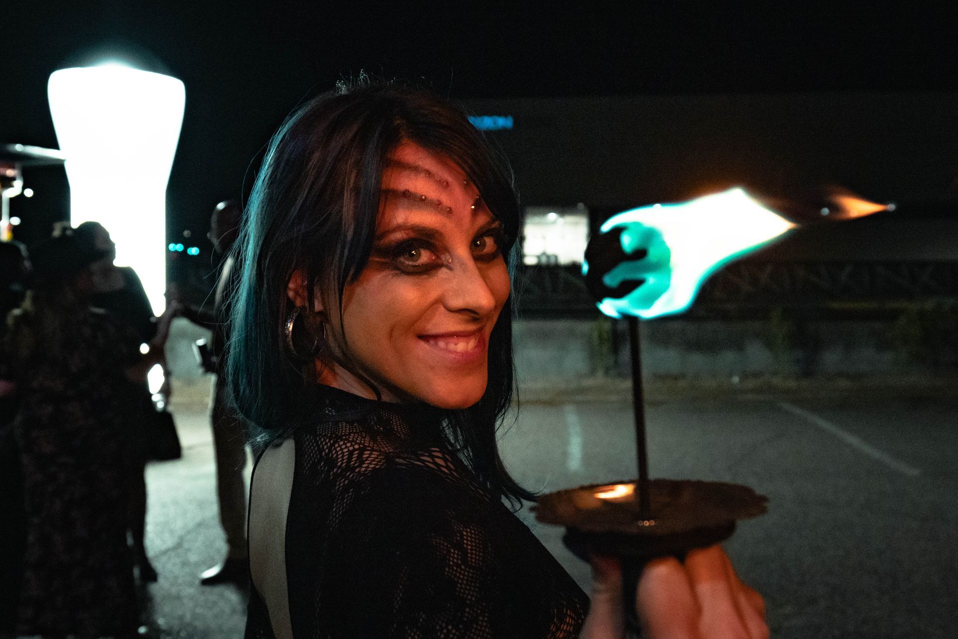 A woman in a black dress is holding a candle in her hand.