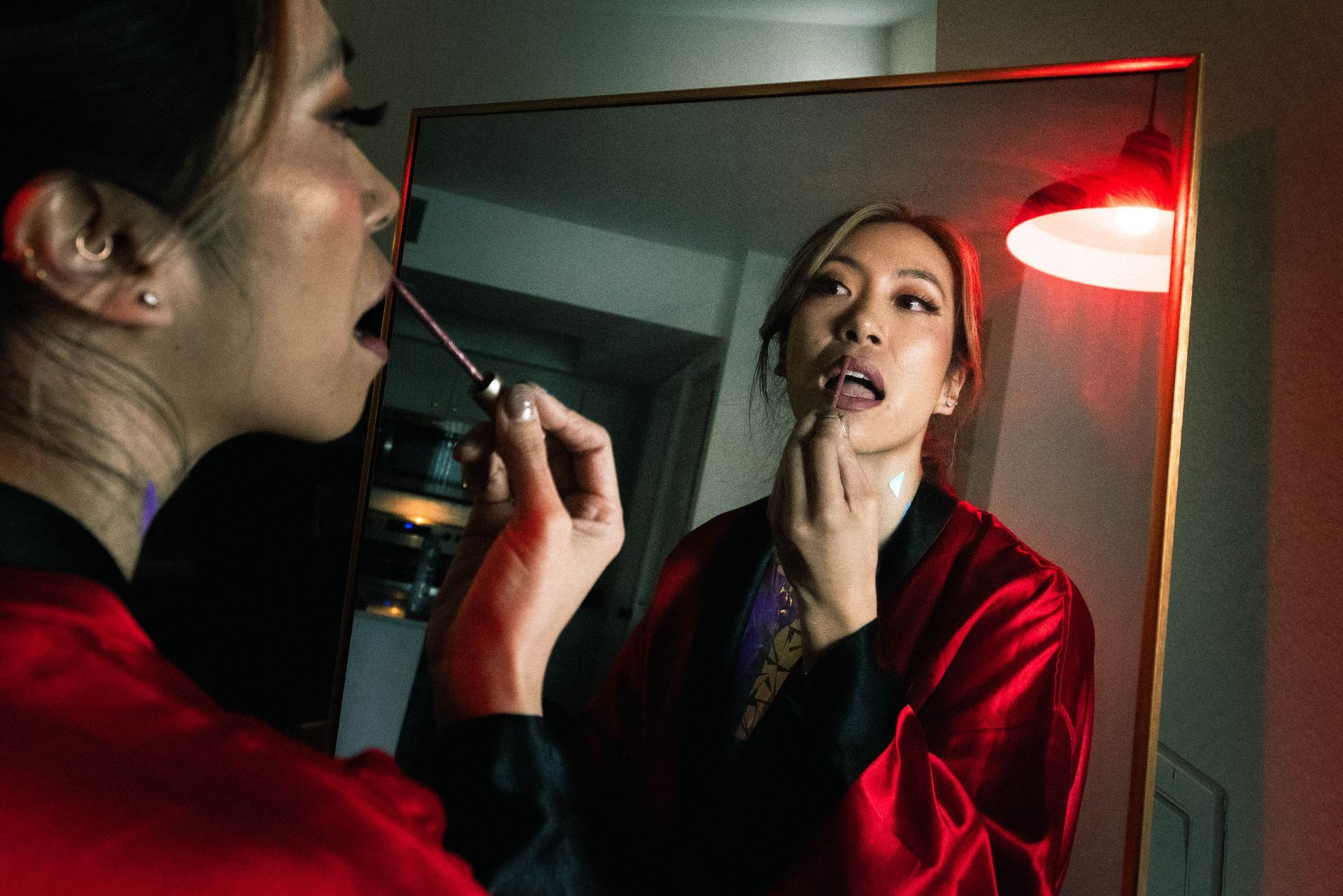 A woman is applying lipstick in front of a mirror.