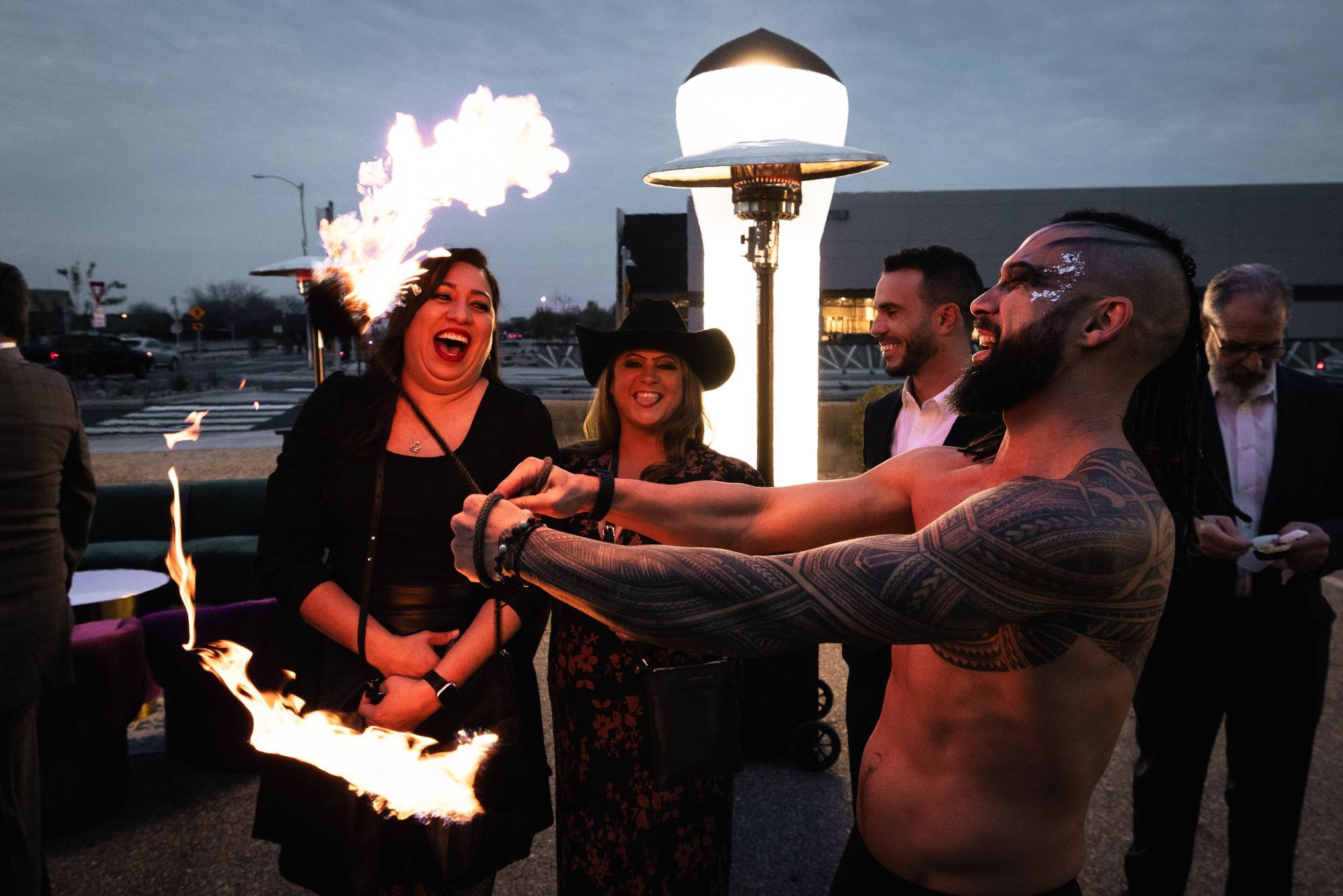 A man without a shirt is holding a torch with flames coming out of it.