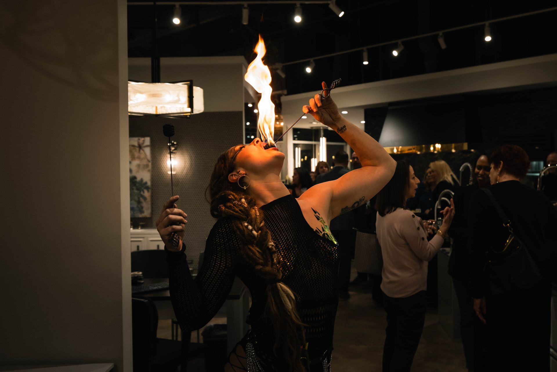 A woman is holding a fireball in her mouth in a room.
