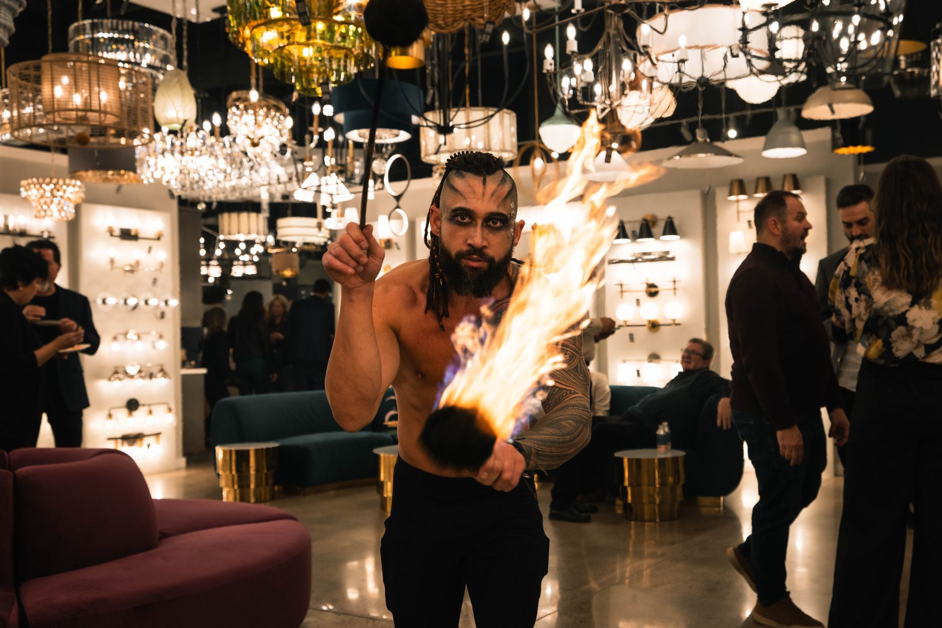 A man without a shirt is holding a torch with flames coming out of it.