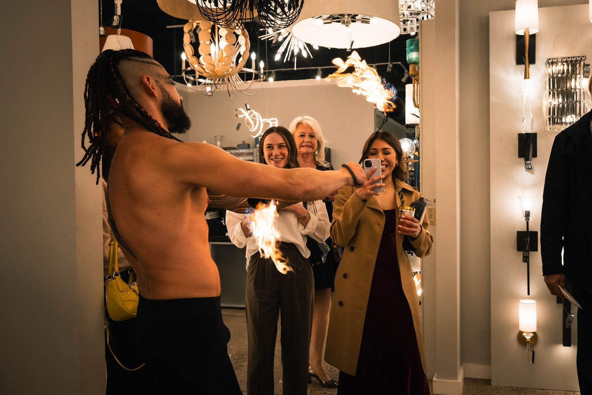 A man without a shirt is holding a fireball in front of a group of people.