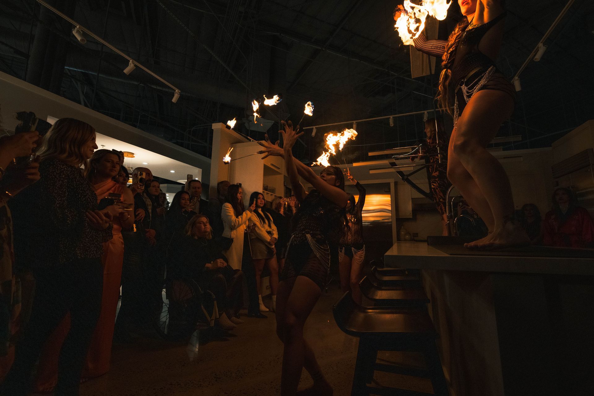A group of people are standing in a dark room watching a fire show.