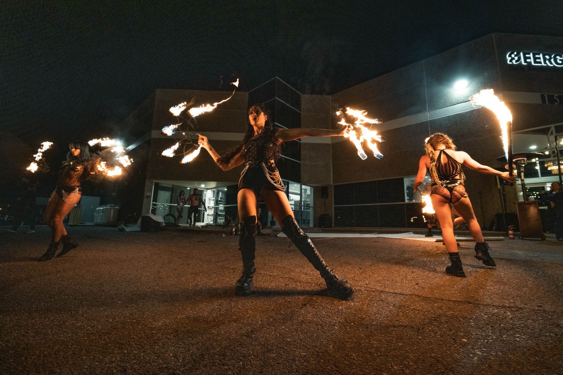 A group of women are performing fire shows in front of a building.