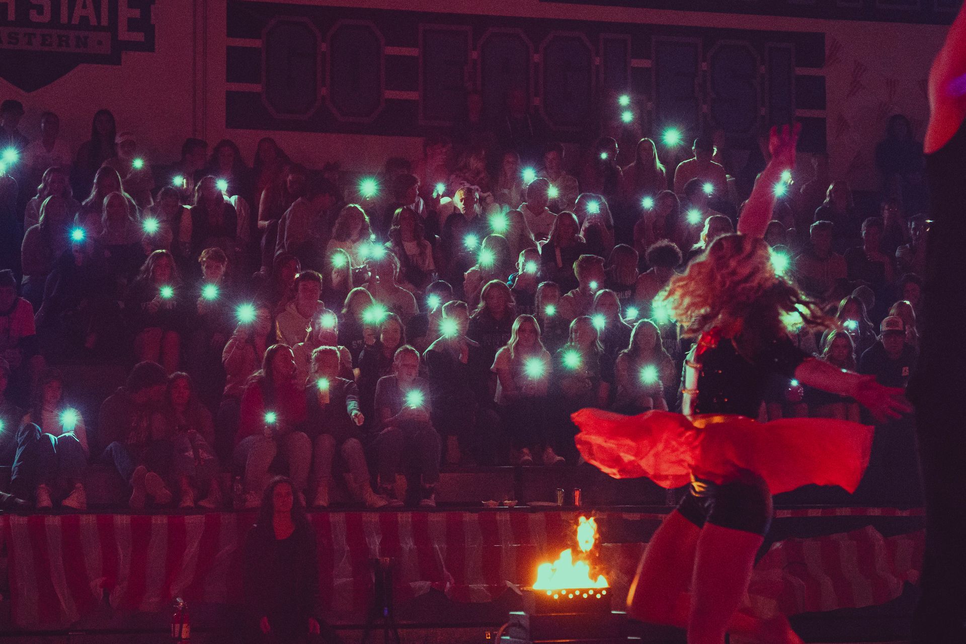 A woman in a red dress is dancing in front of a crowd of people.