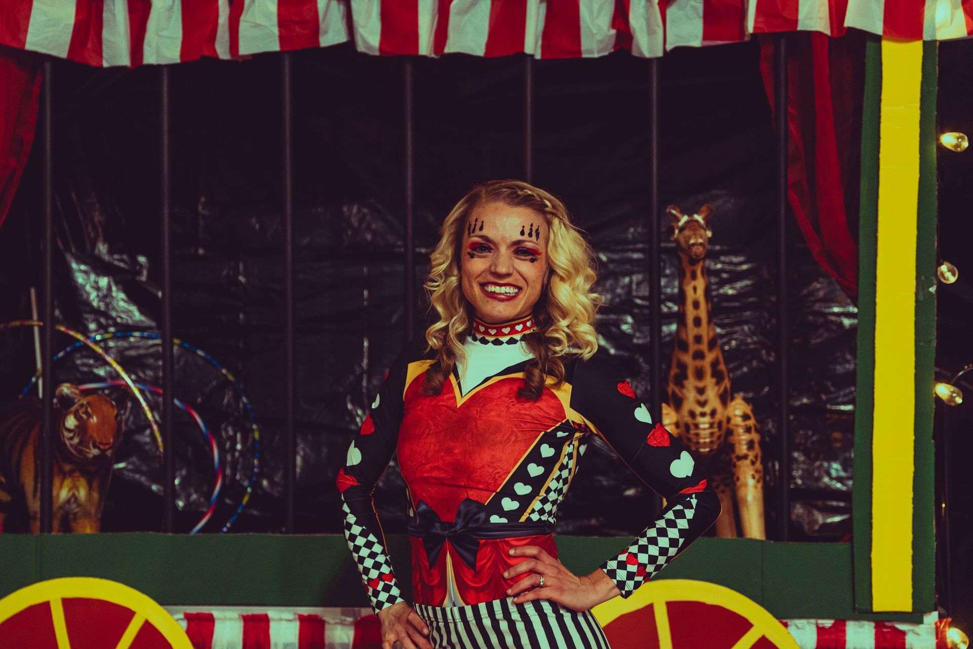 A woman in a circus costume is standing in front of a giraffe statue.
