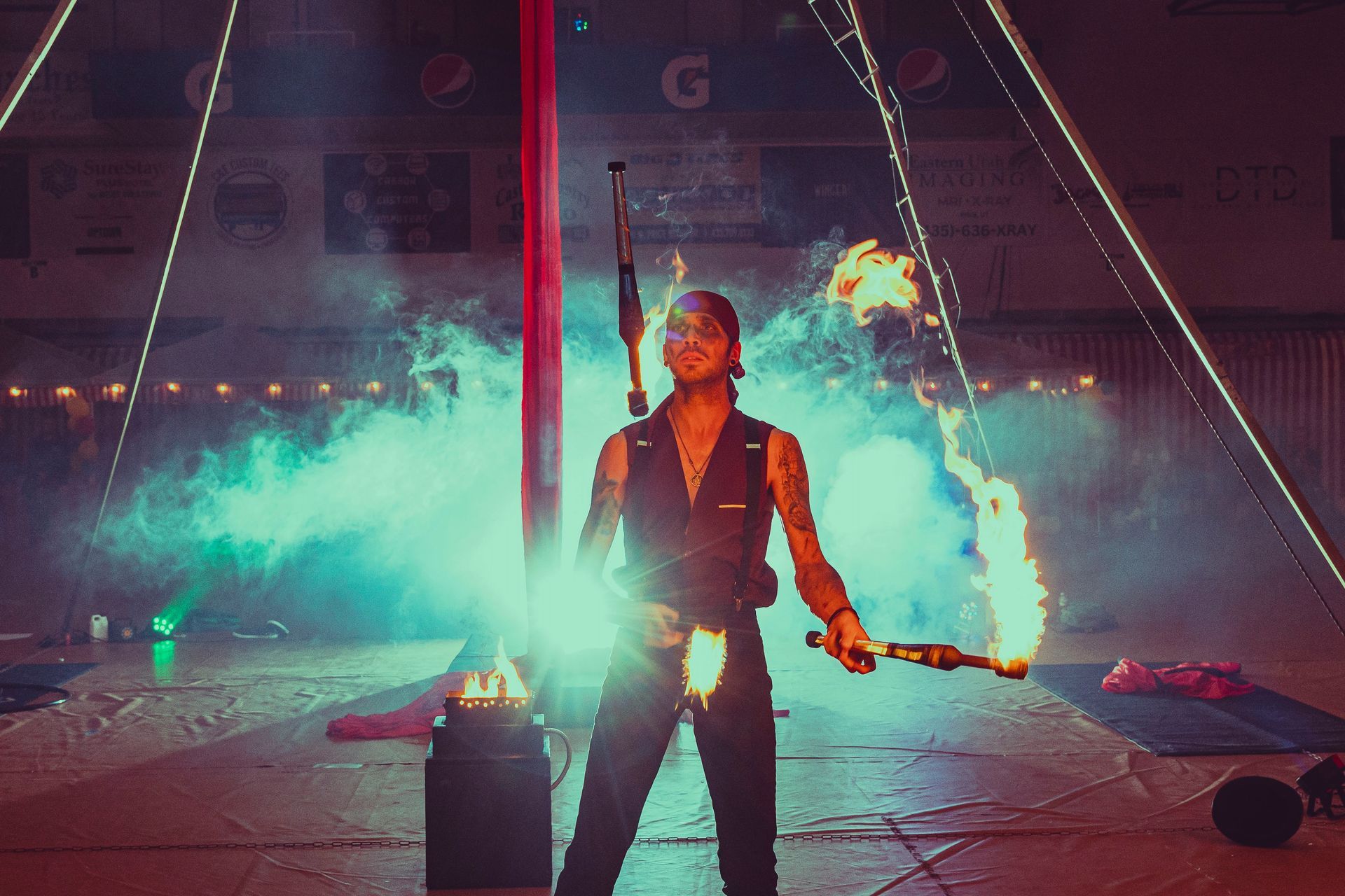 A man is holding a fire stick in a circus tent.