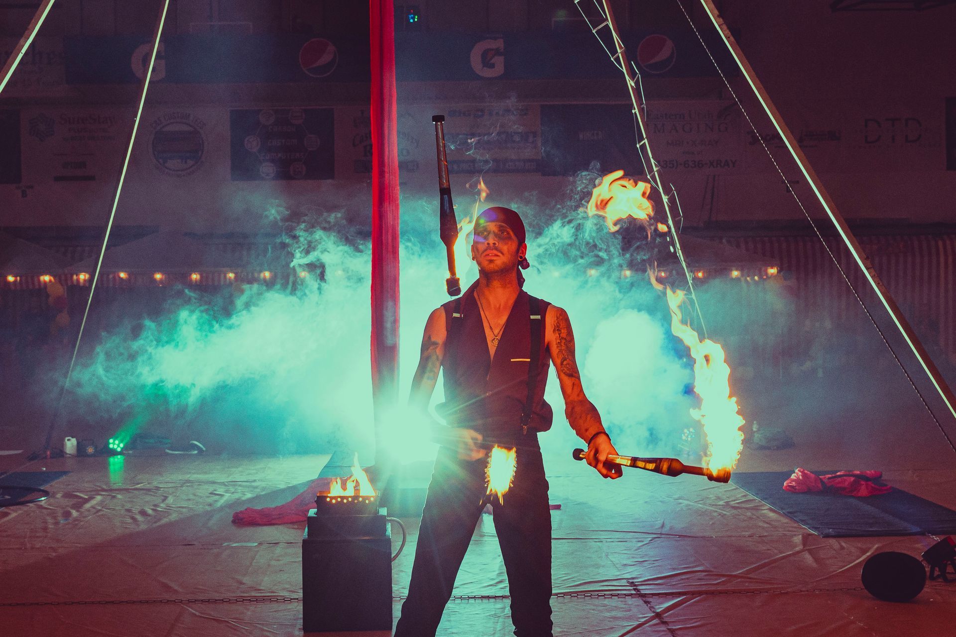 A man is holding a fire stick in a circus tent.