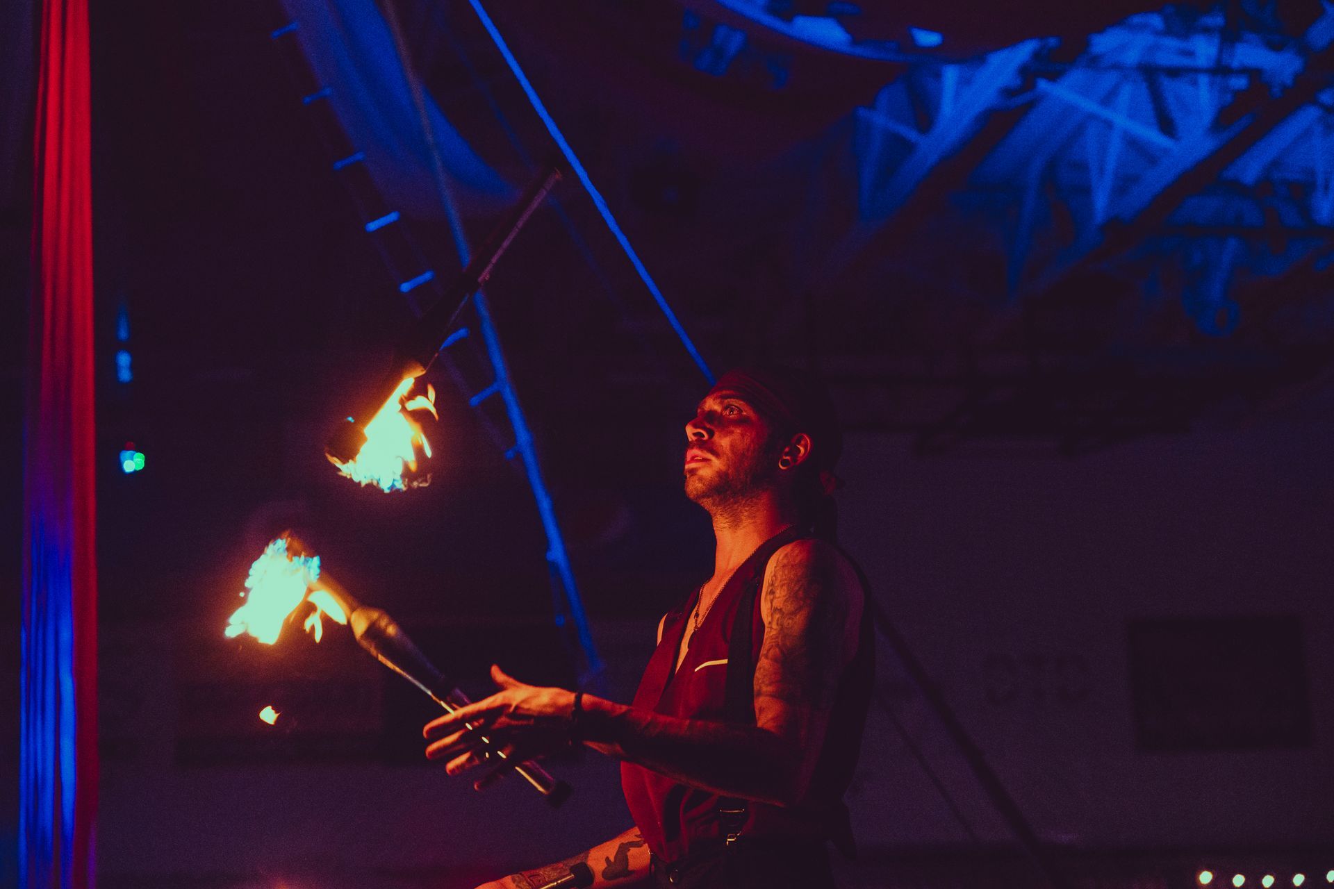 A man is juggling fire in a dark room.