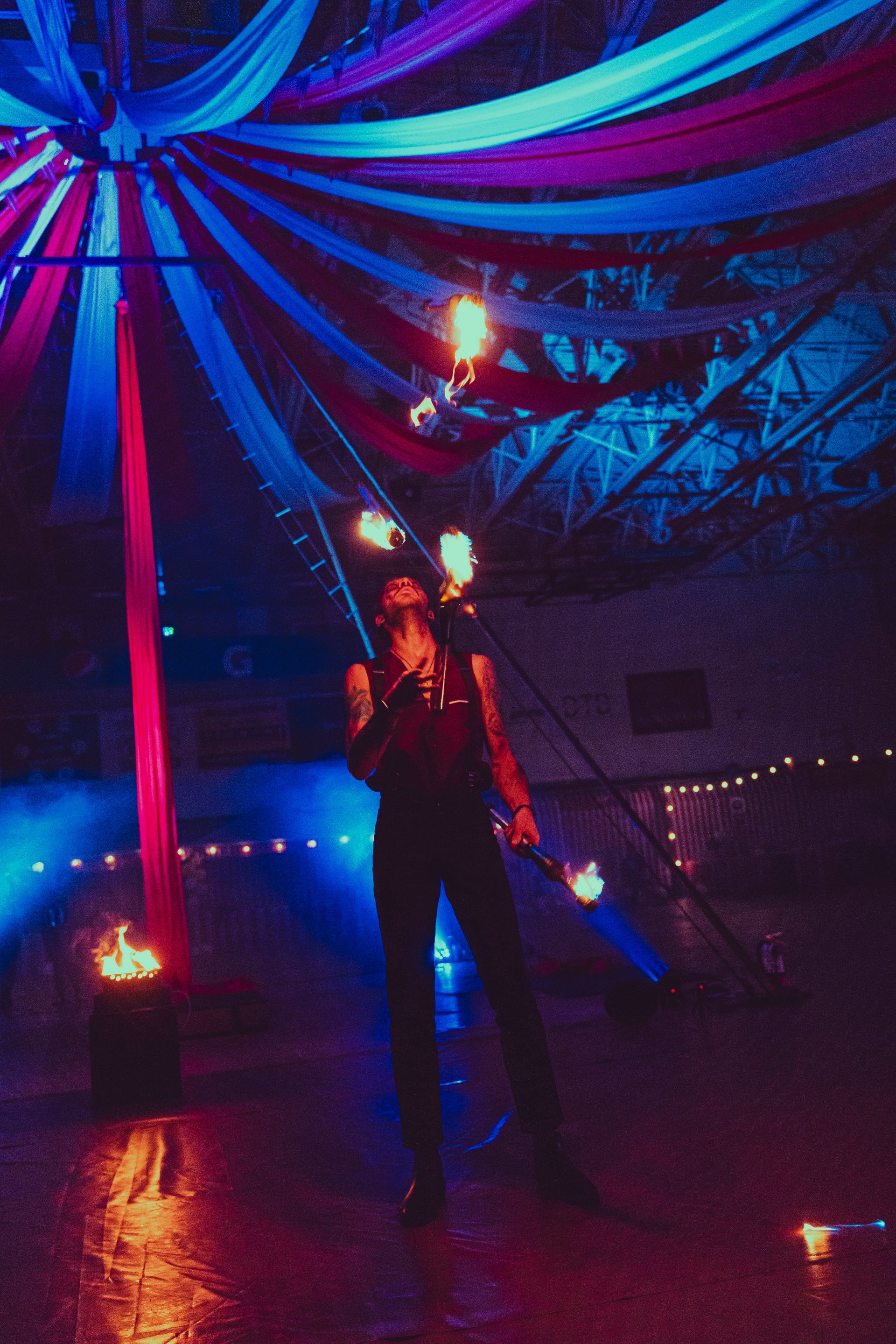 A man is juggling fire in a dark room.