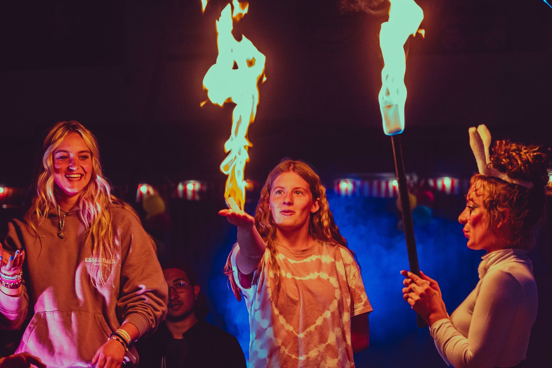 A group of people are standing in front of a fire.