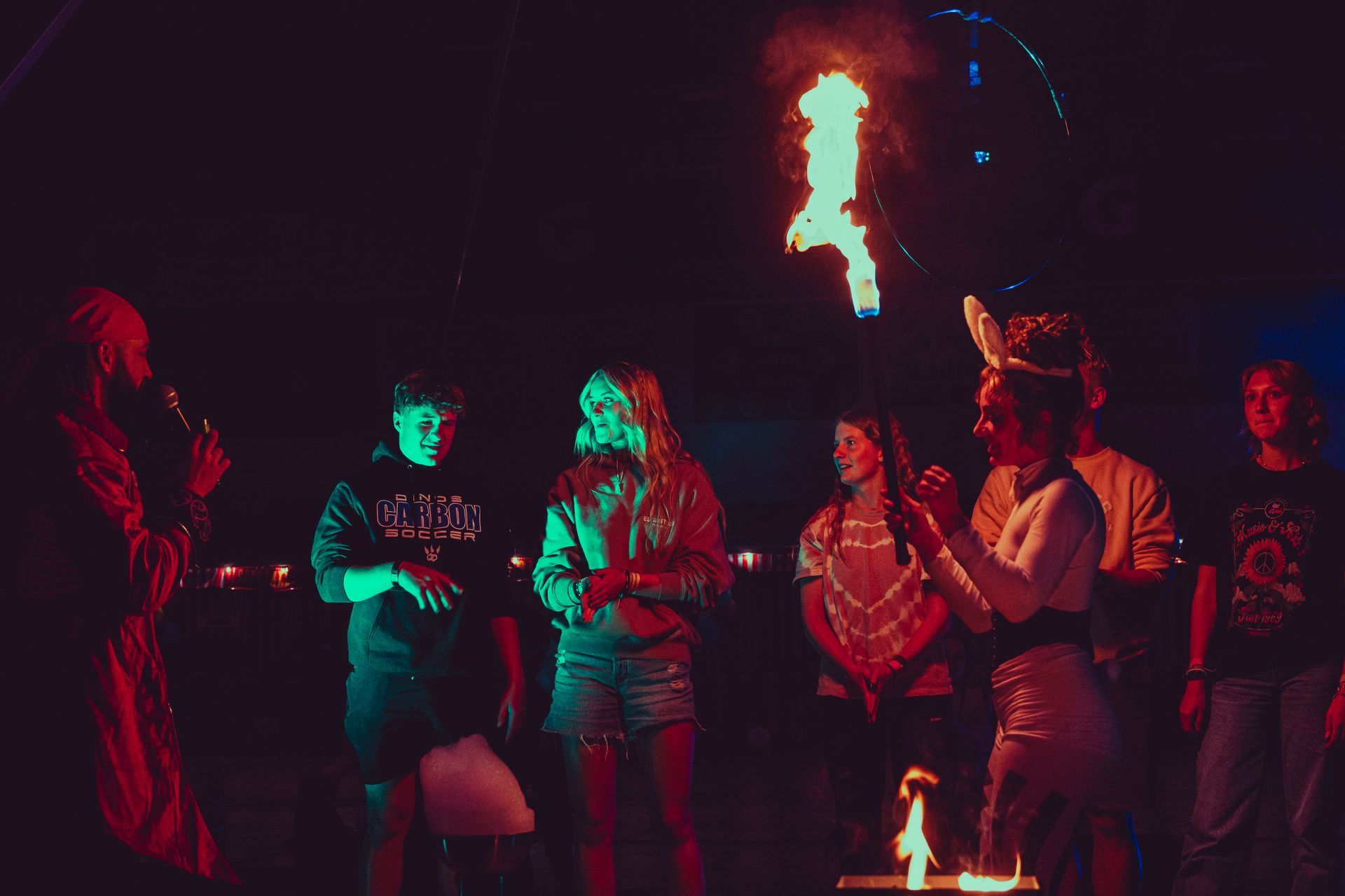 A group of people are standing around a fire at night.