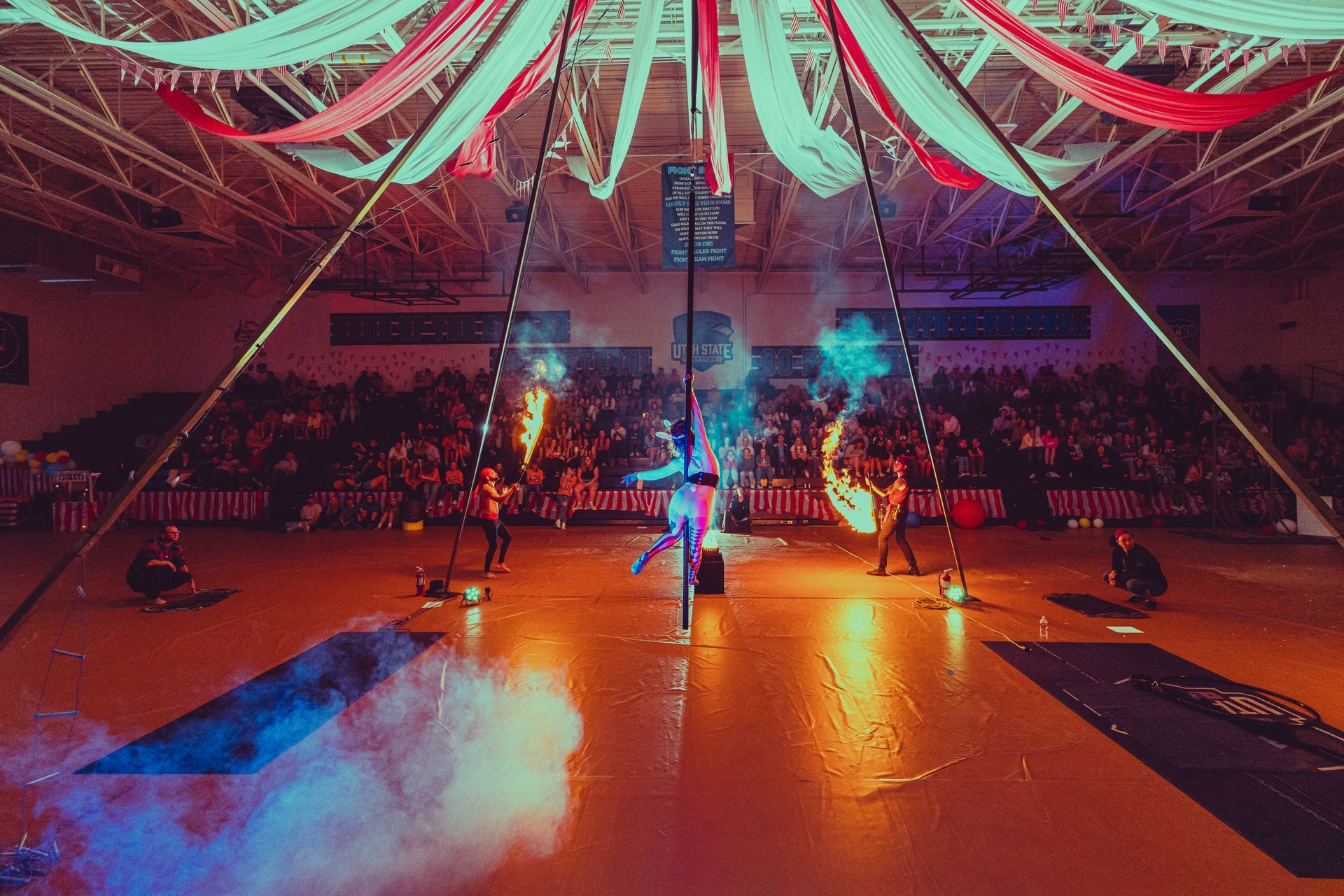 A group of people are performing a fire show in a gym.