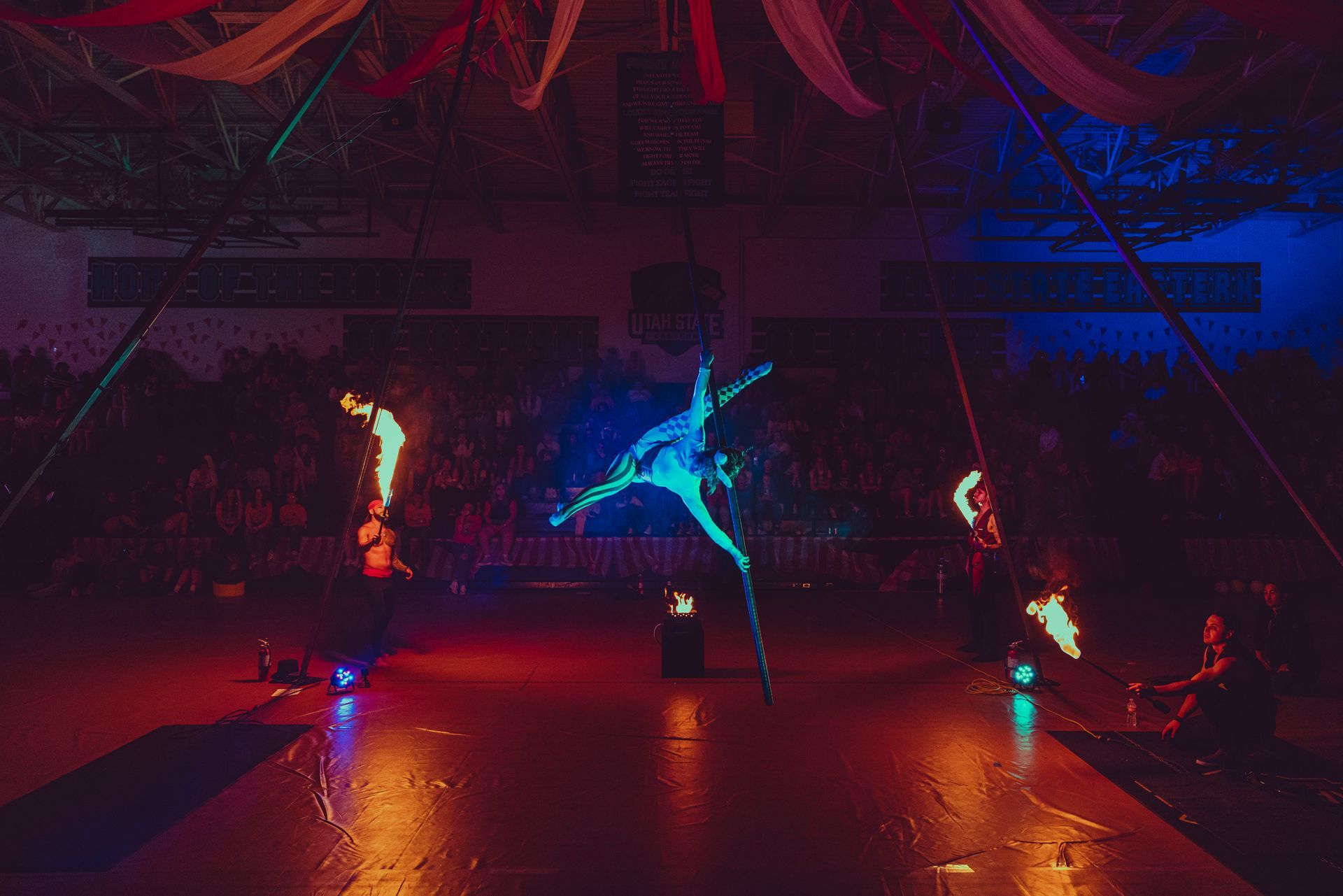 A group of people are performing aerial acrobatics in front of a crowd.
