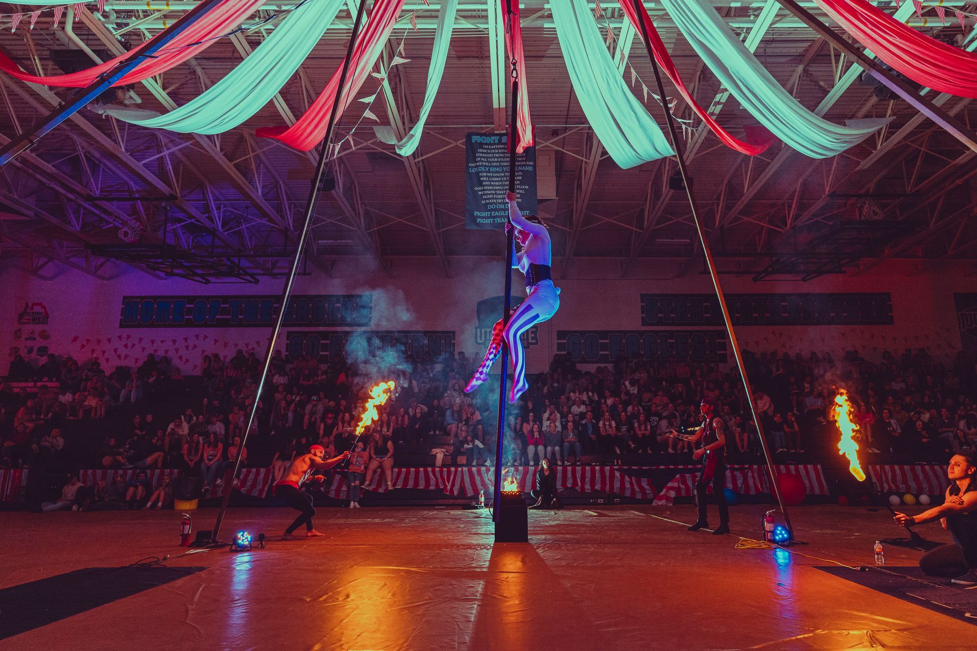 A group of people are performing aerial acrobatics in a gym.