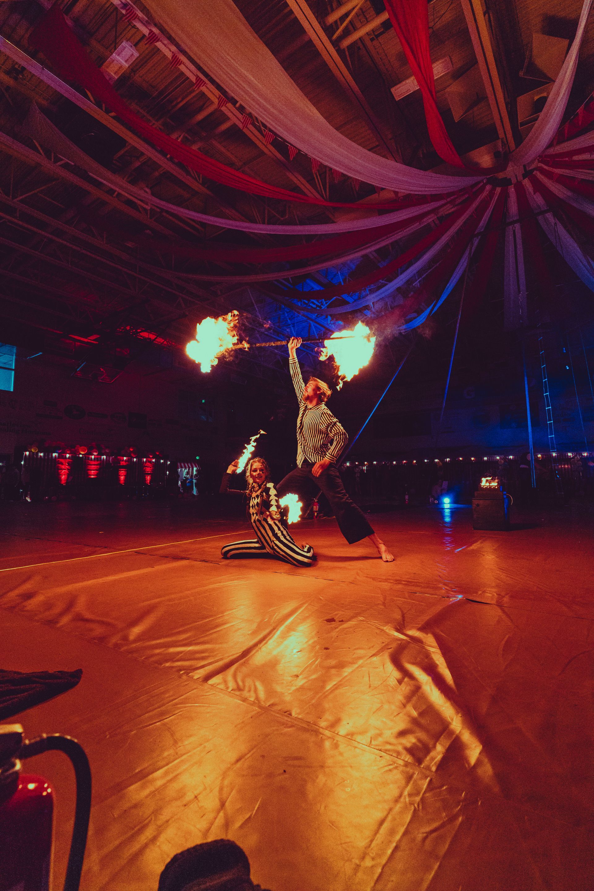 Two people are performing a fire show in a dark room.