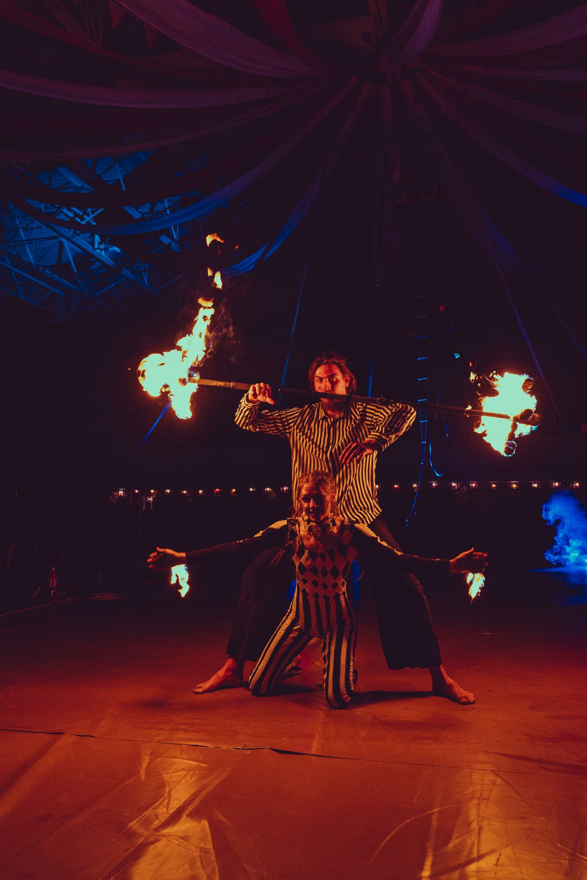 A group of people are performing a fire show in a dark room.