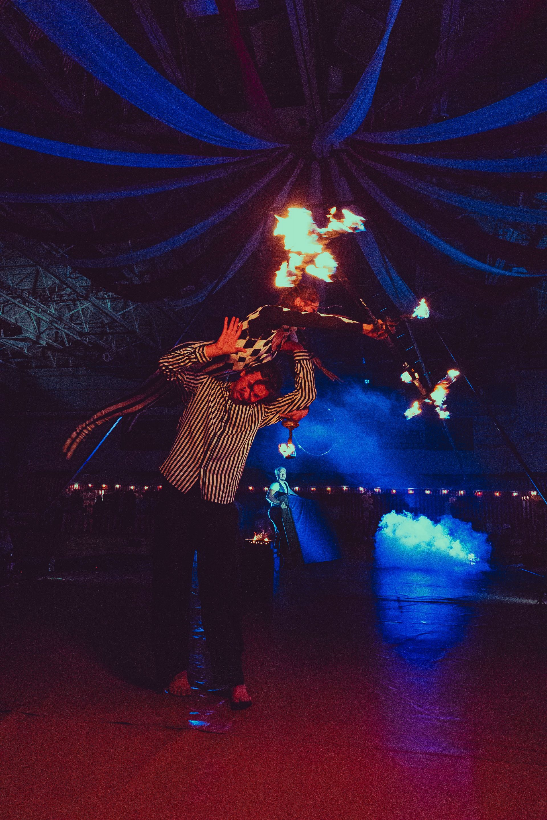 A man is holding a torch with fire on it in a dark room.
