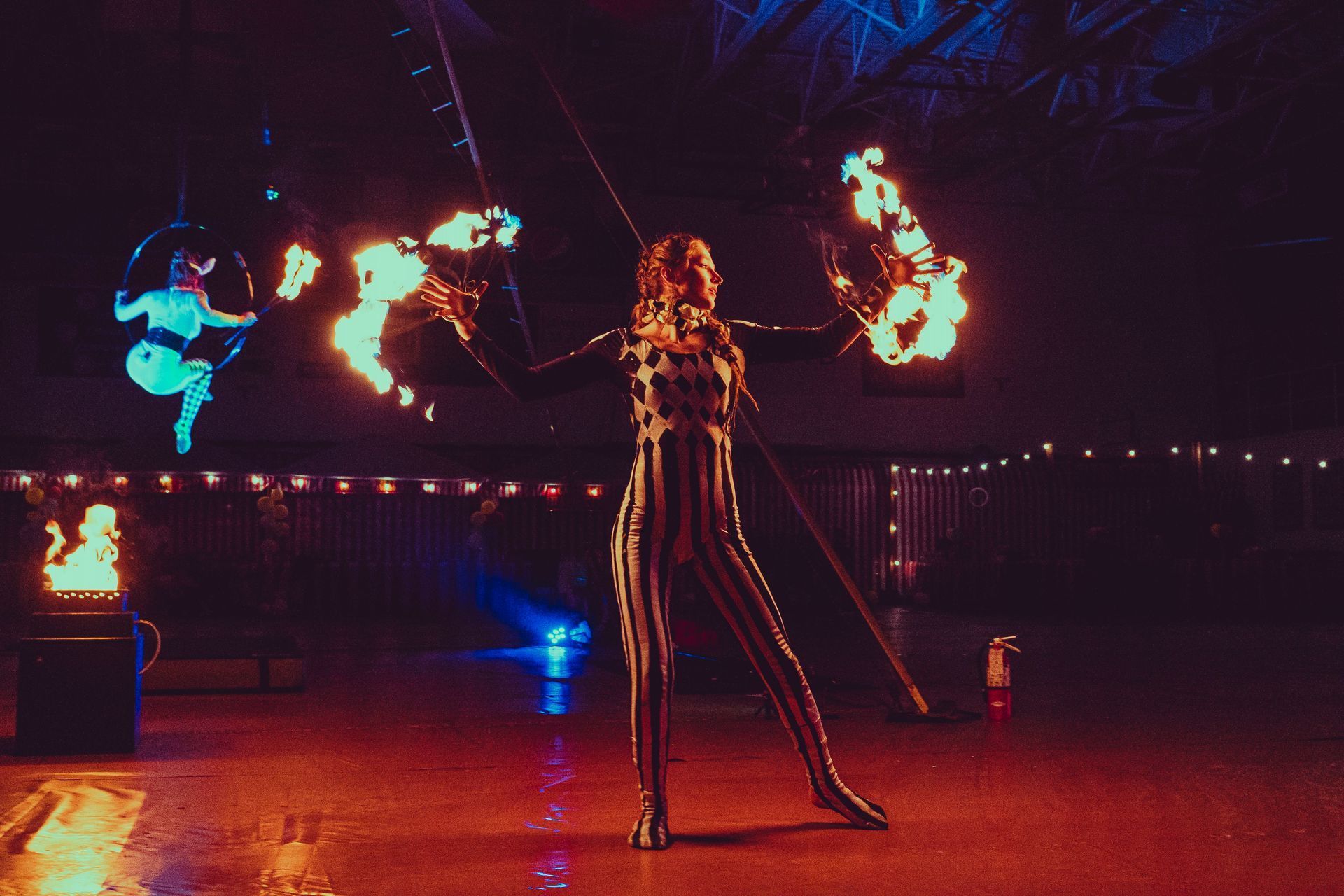 A woman performing with Fire Fans indoors.