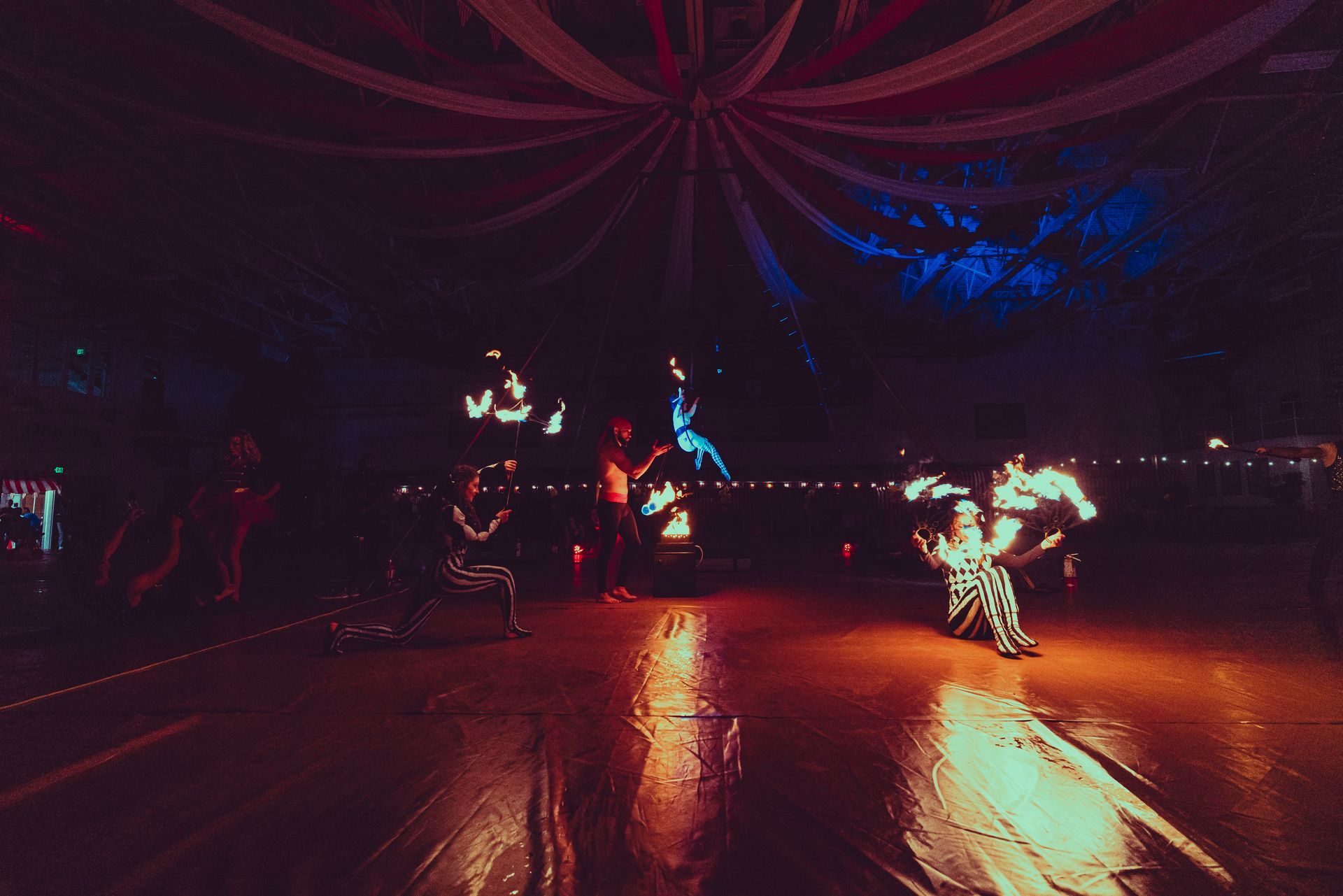 A group of people are dancing with fire in a dark room.
