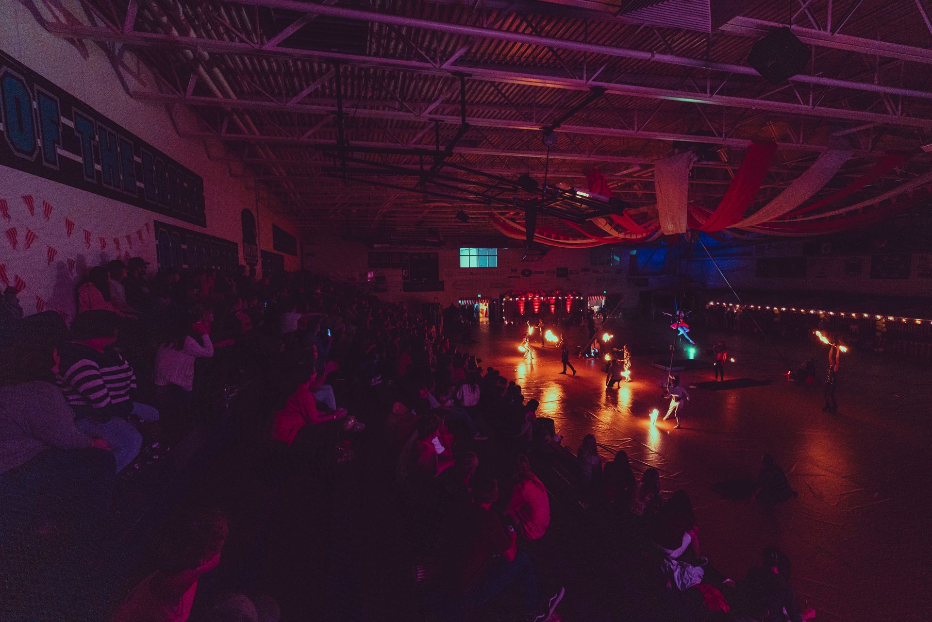 A large group of people are sitting in a dark room at a roller rink.