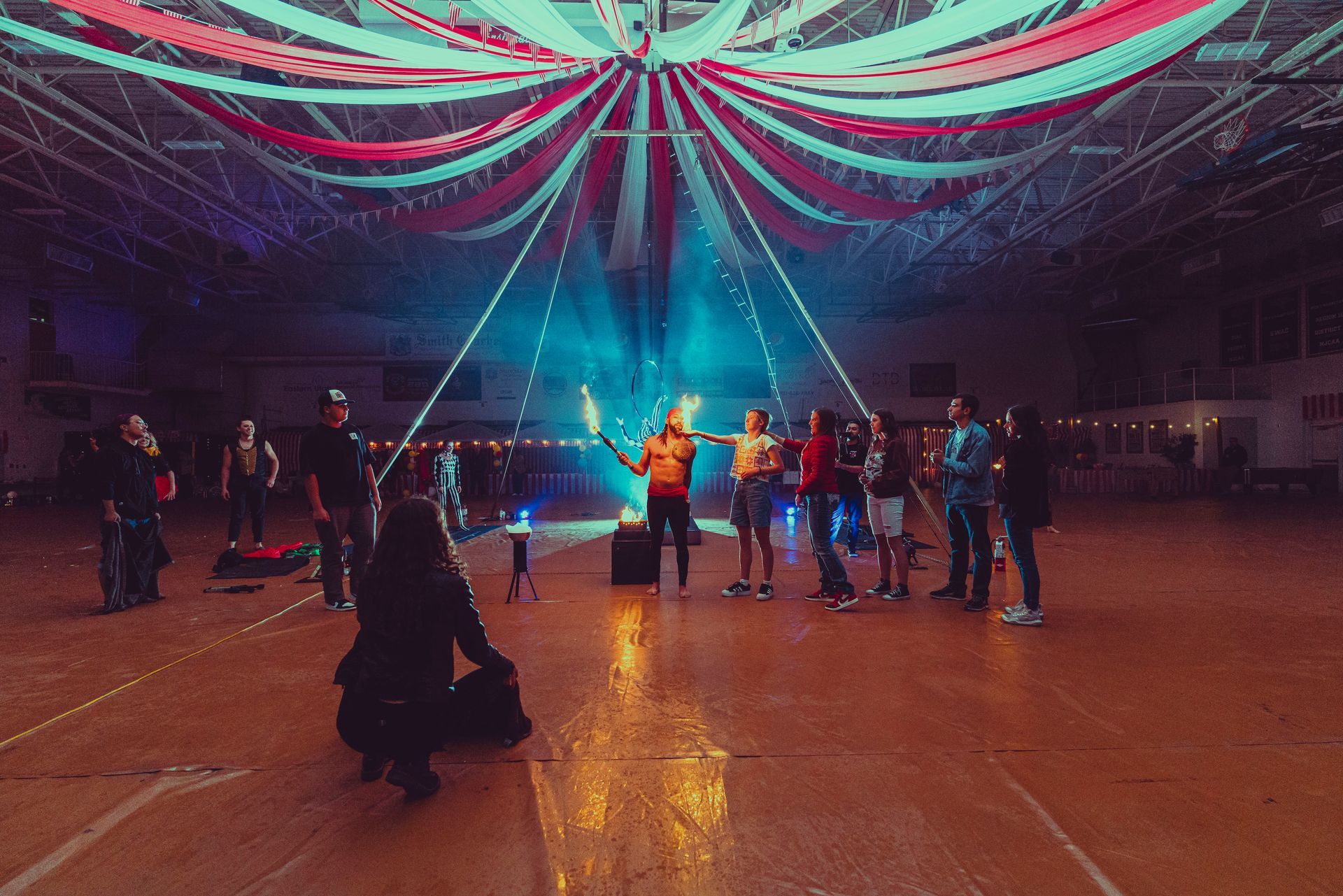 A group of people are standing in a large room holding torches.