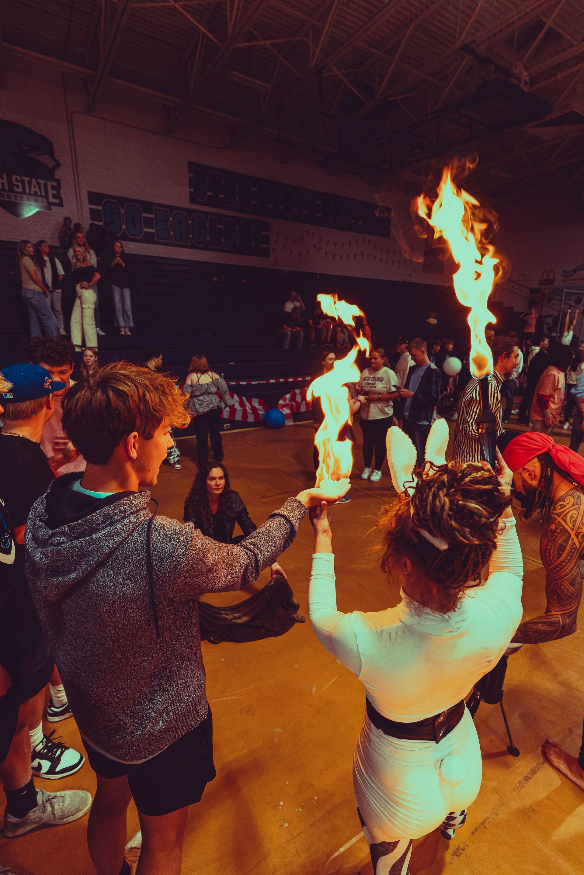 A group of people are holding flaming torches in a gym.
