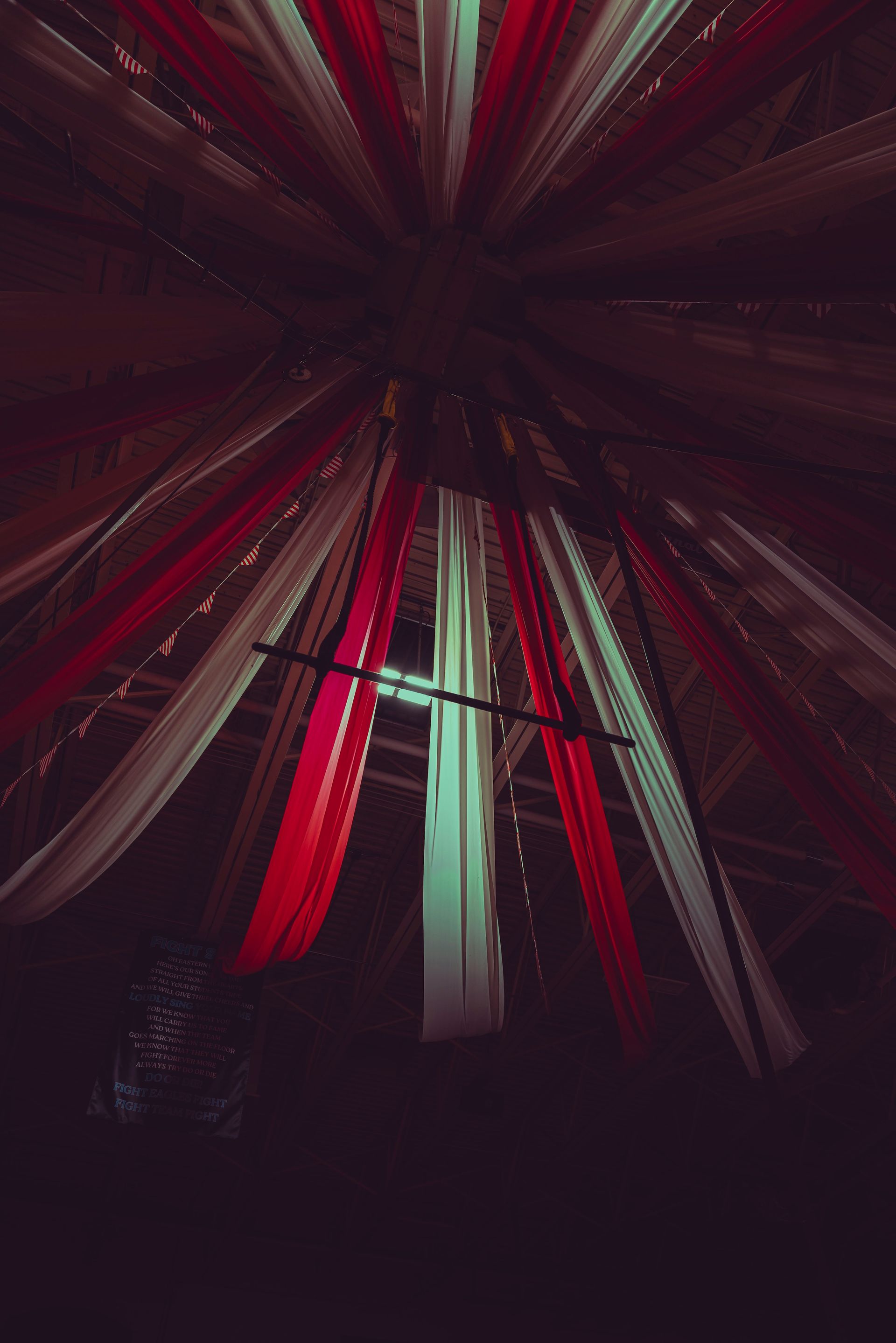 Looking up at a ceiling with red , white and green ribbons hanging from it.
