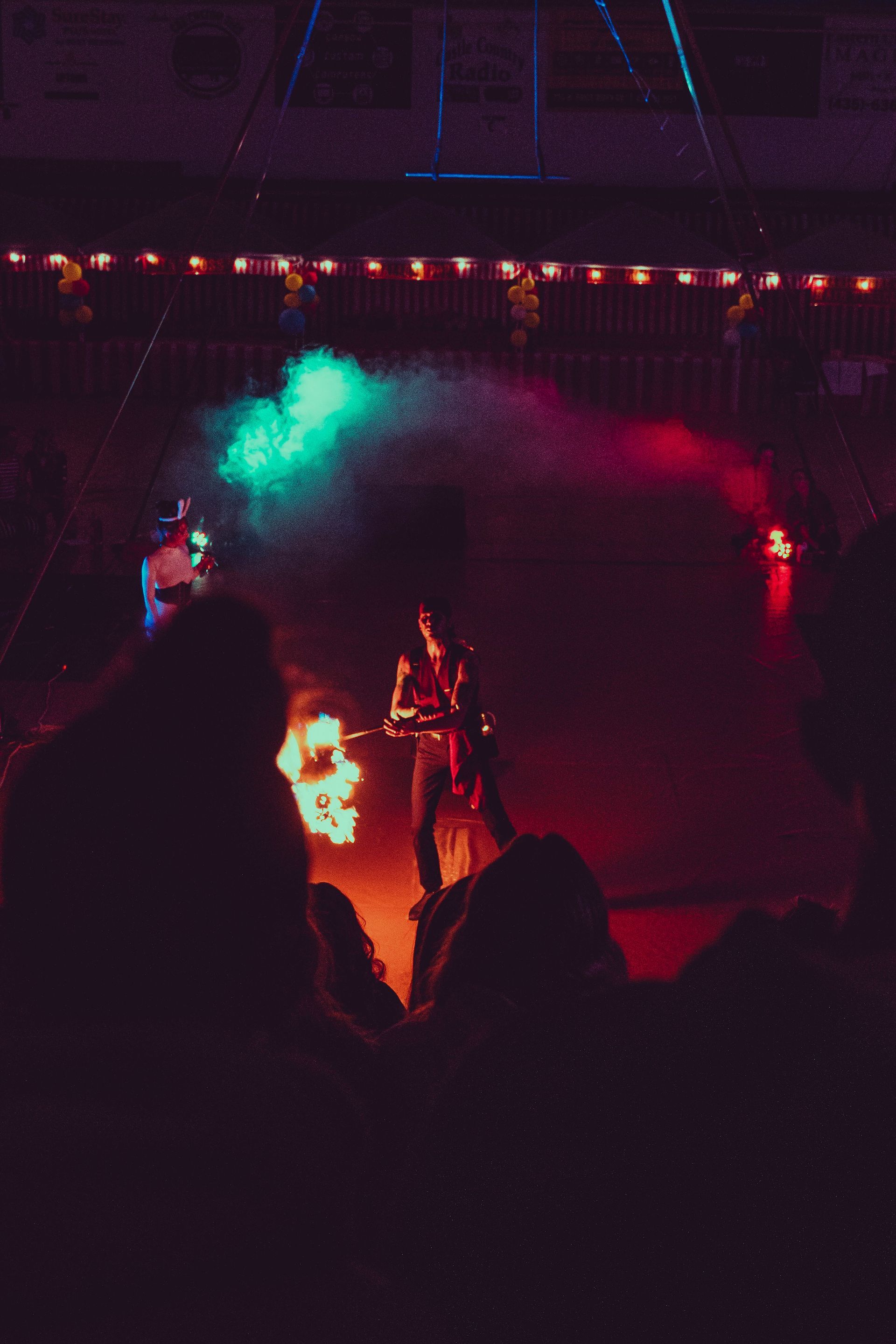 A group of people are sitting in a dark room watching a fire show.