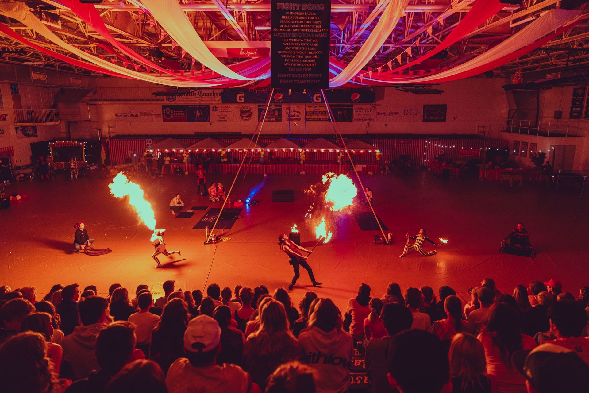 A crowd of people are watching a fire show in a stadium.