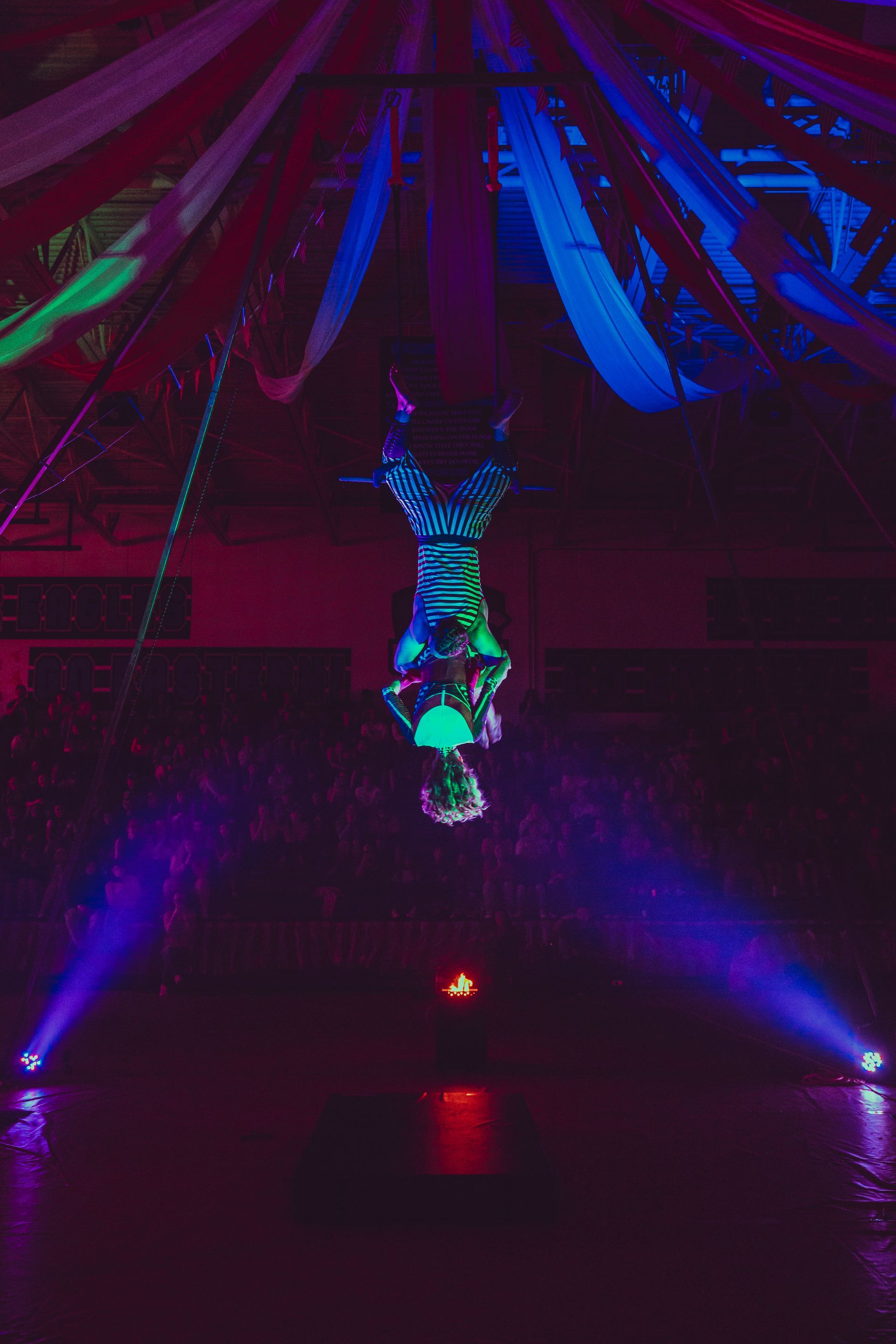 A woman is doing a handstand in the air in a dark room.