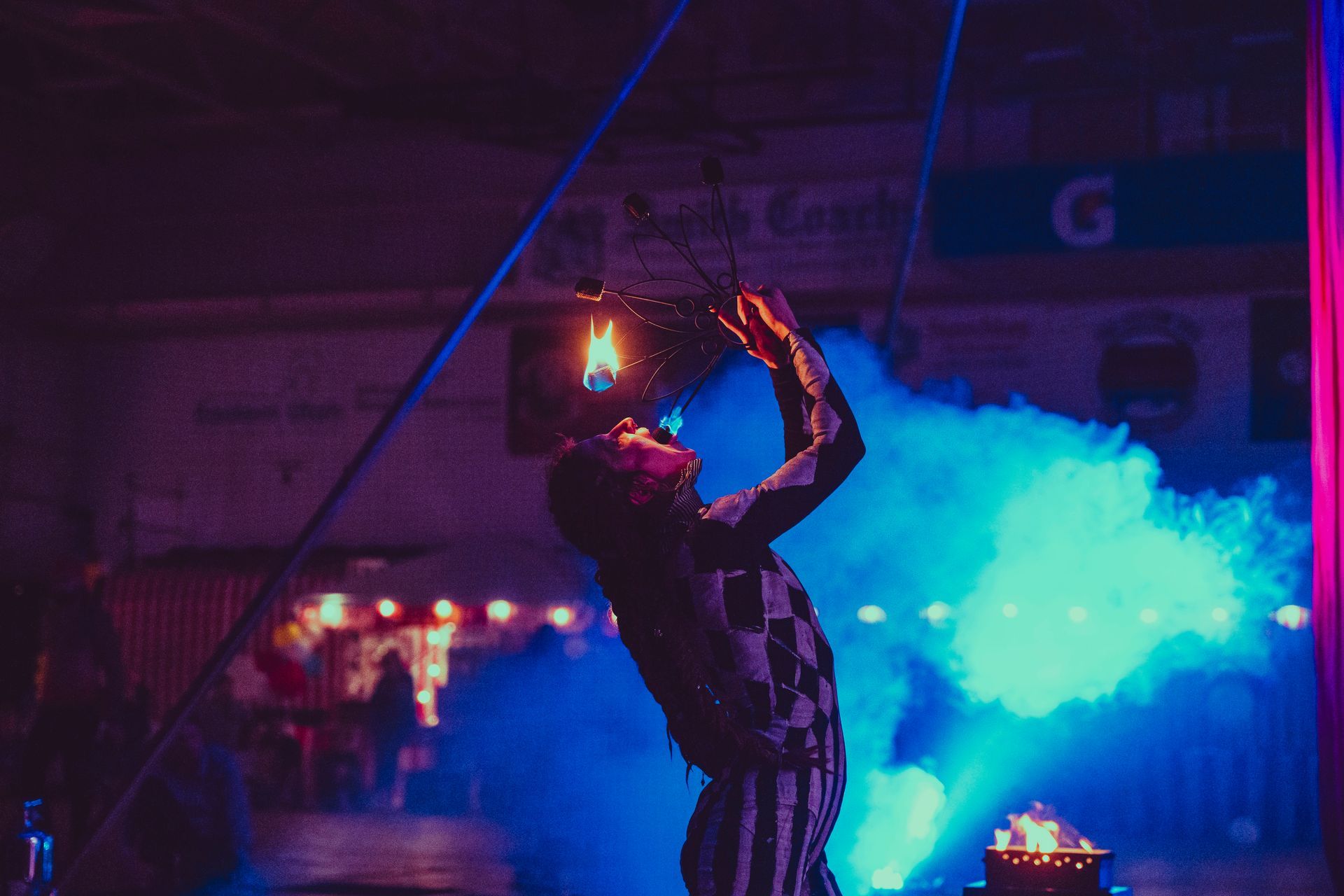 A man is juggling fire in his mouth while standing on a rope.
