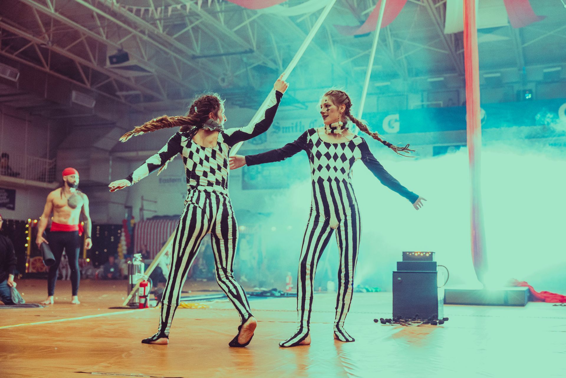 Two women are performing aerial acrobatics in a gym.