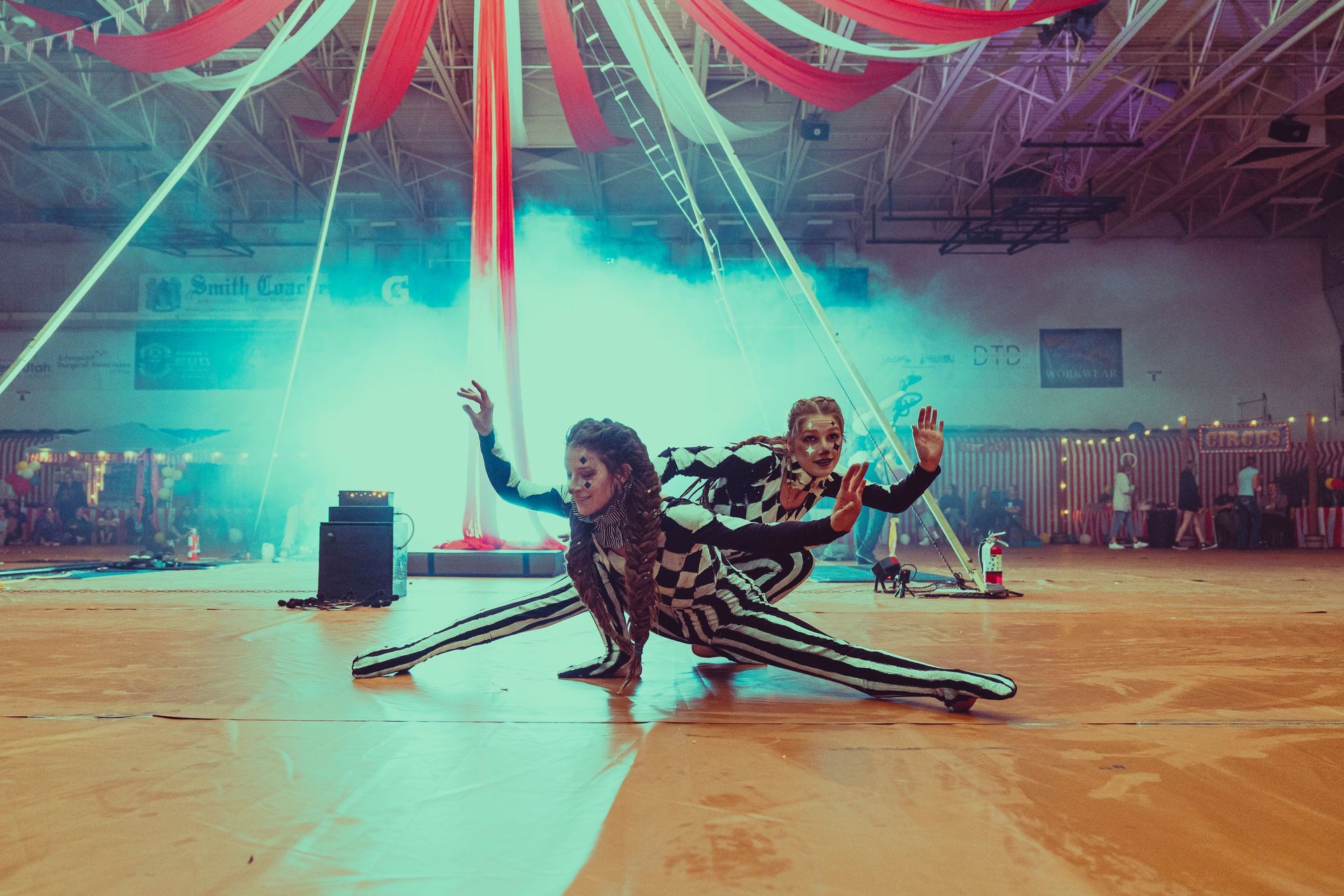 Two women are performing aerial acrobatics in a gym.
