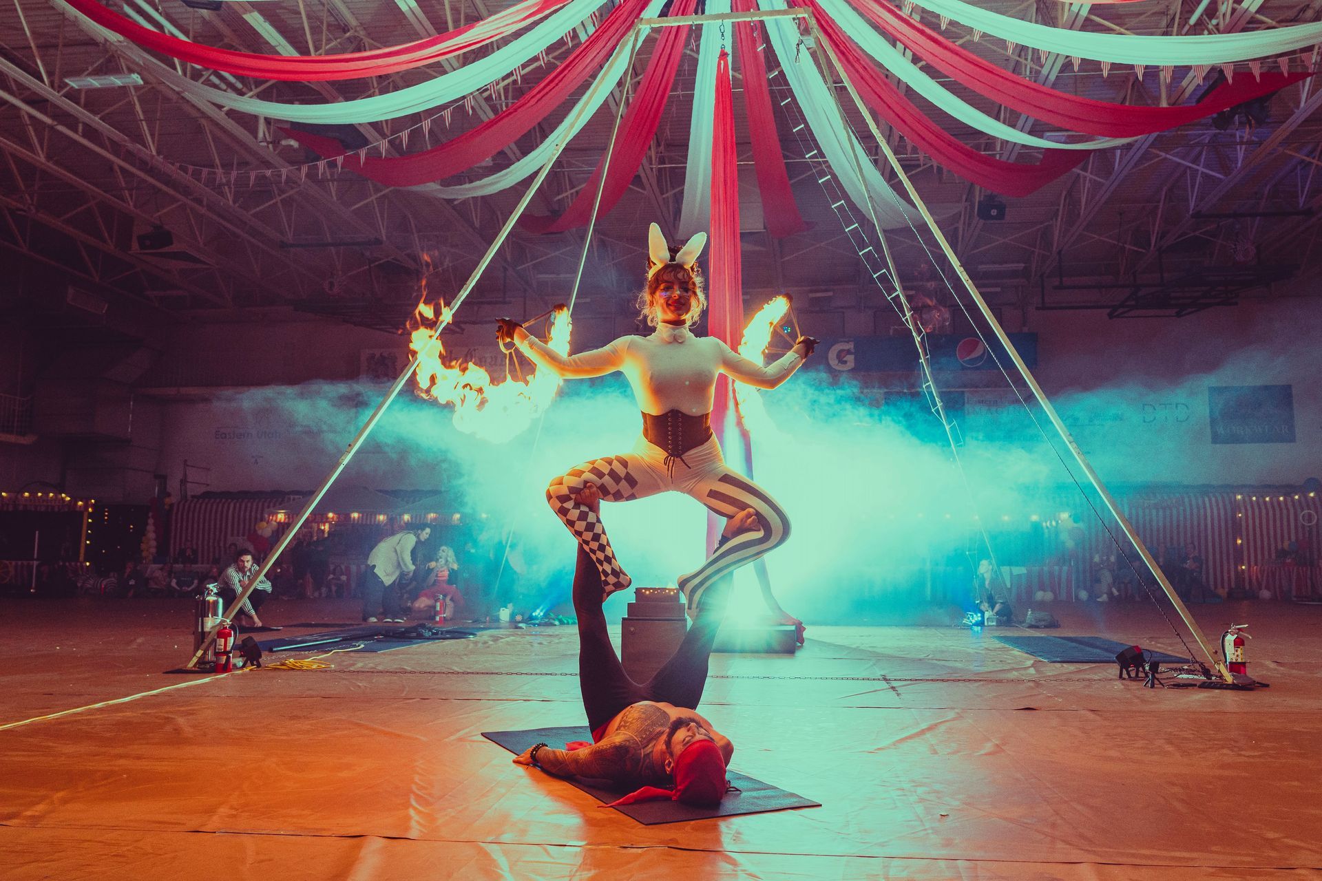 A man and a woman are performing aerial acrobatics with fire.