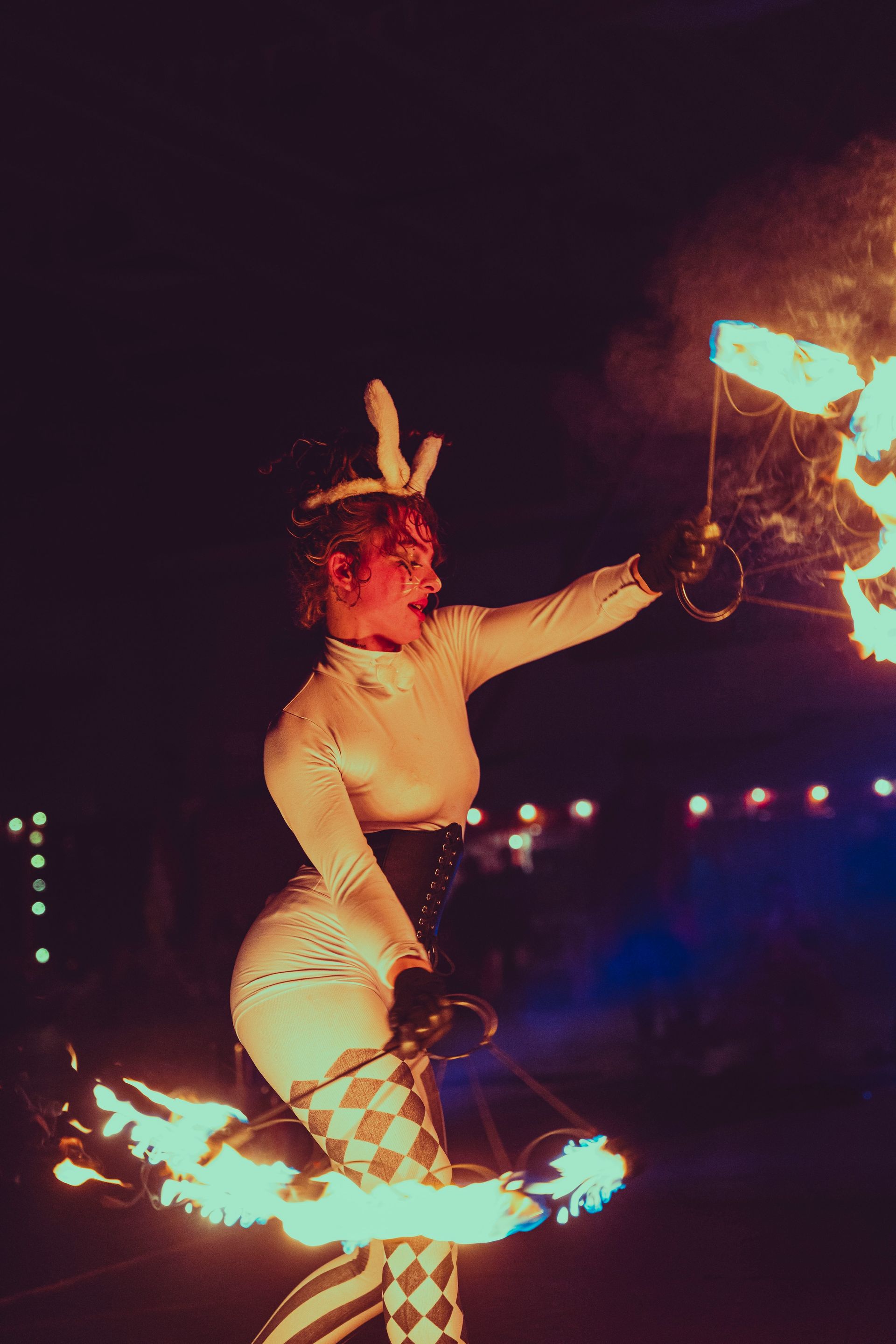 A woman in a costume is holding a fan of fire in her hand.