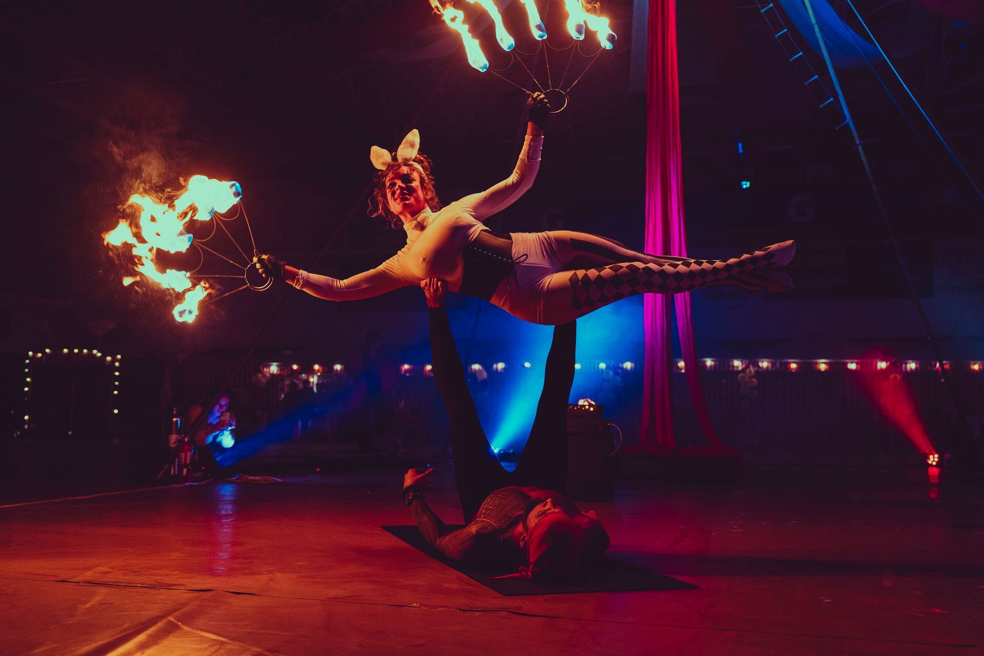 A man and woman performing acrobatics with fire.