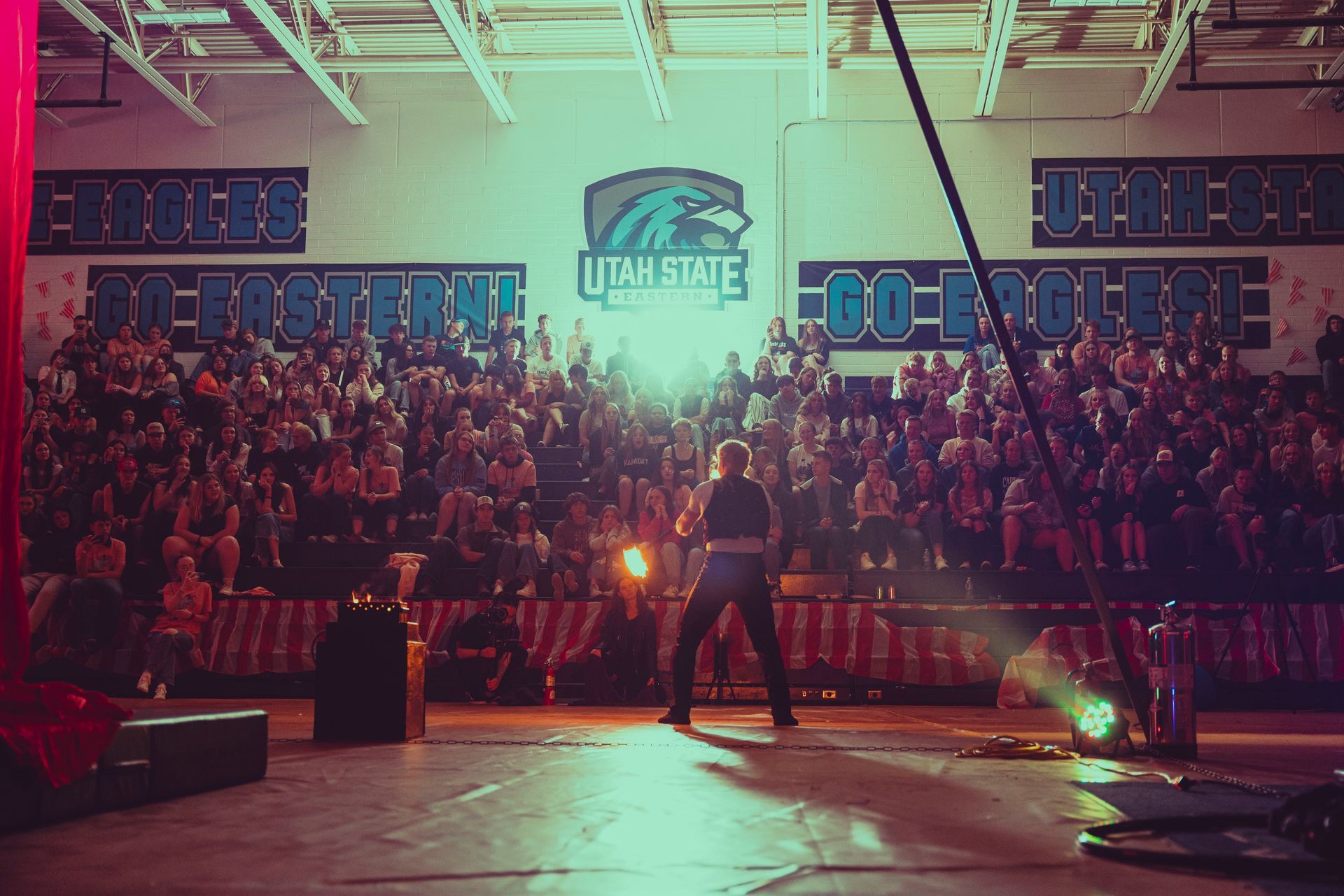 A man is standing in front of a crowd in a gym.